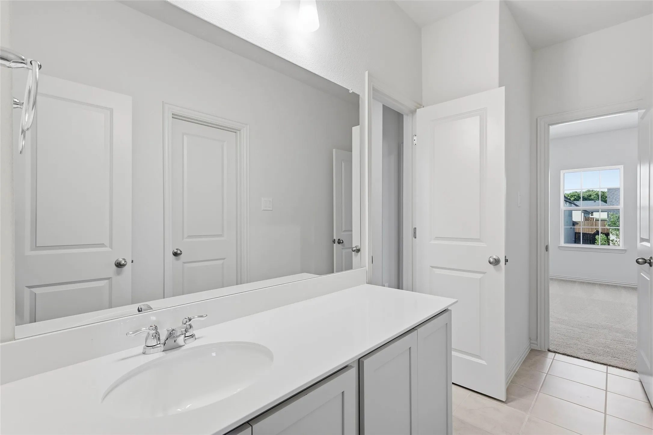 Bathroom with vanity, light tile patterned floors, and light colored carpet