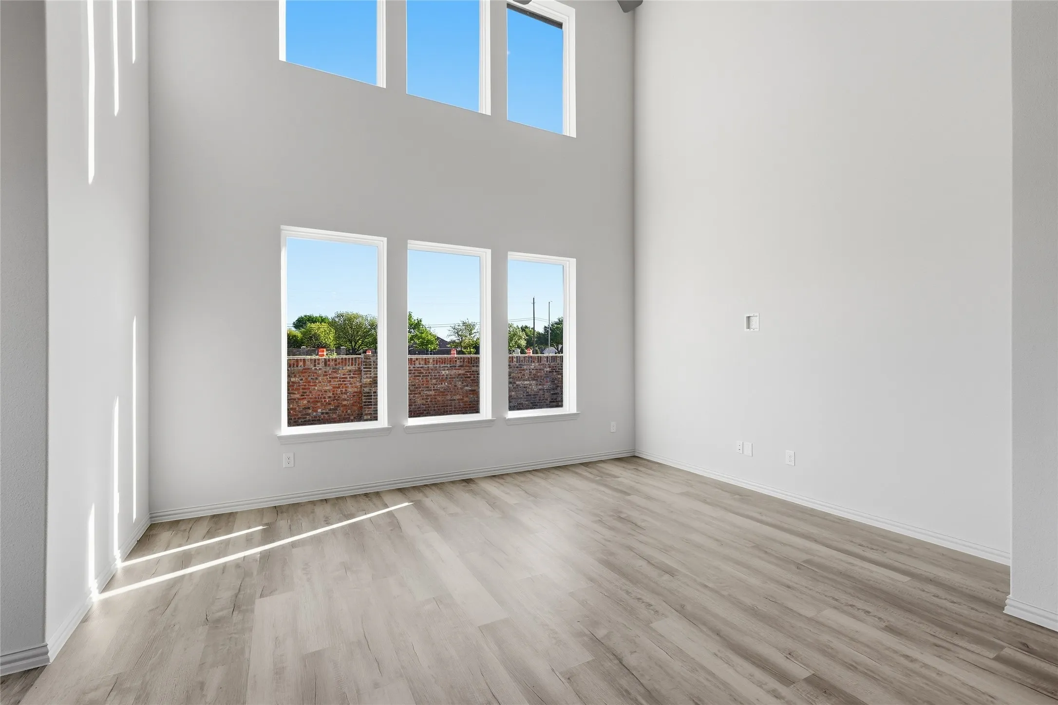 Unfurnished living room featuring light wood-type flooring and a high ceiling