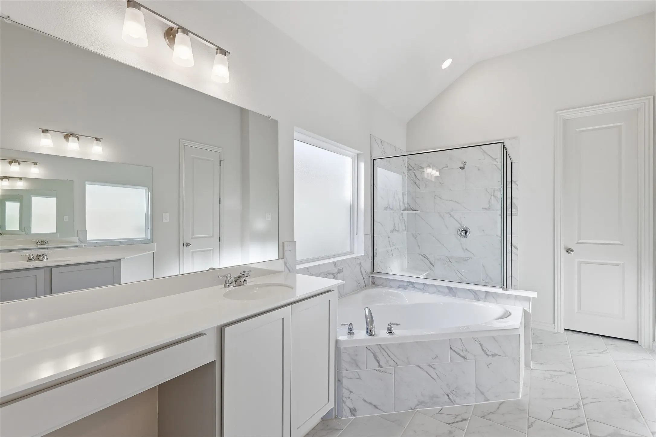 Full bath with a marble finish shower, light marble finish floors, vanity, a garden tub, and lofted ceiling
