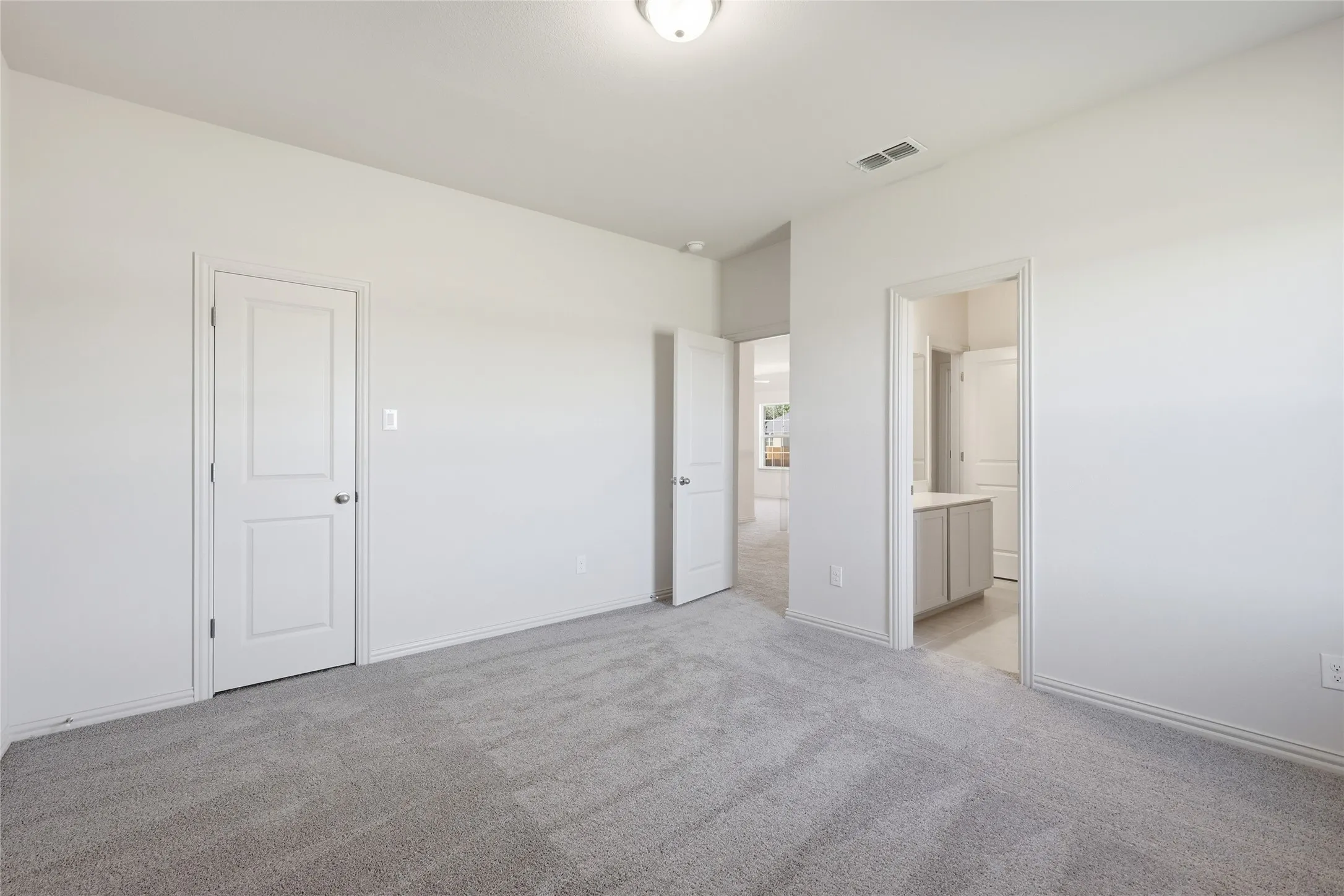 Unfurnished bedroom featuring light colored carpet and connected bathroom