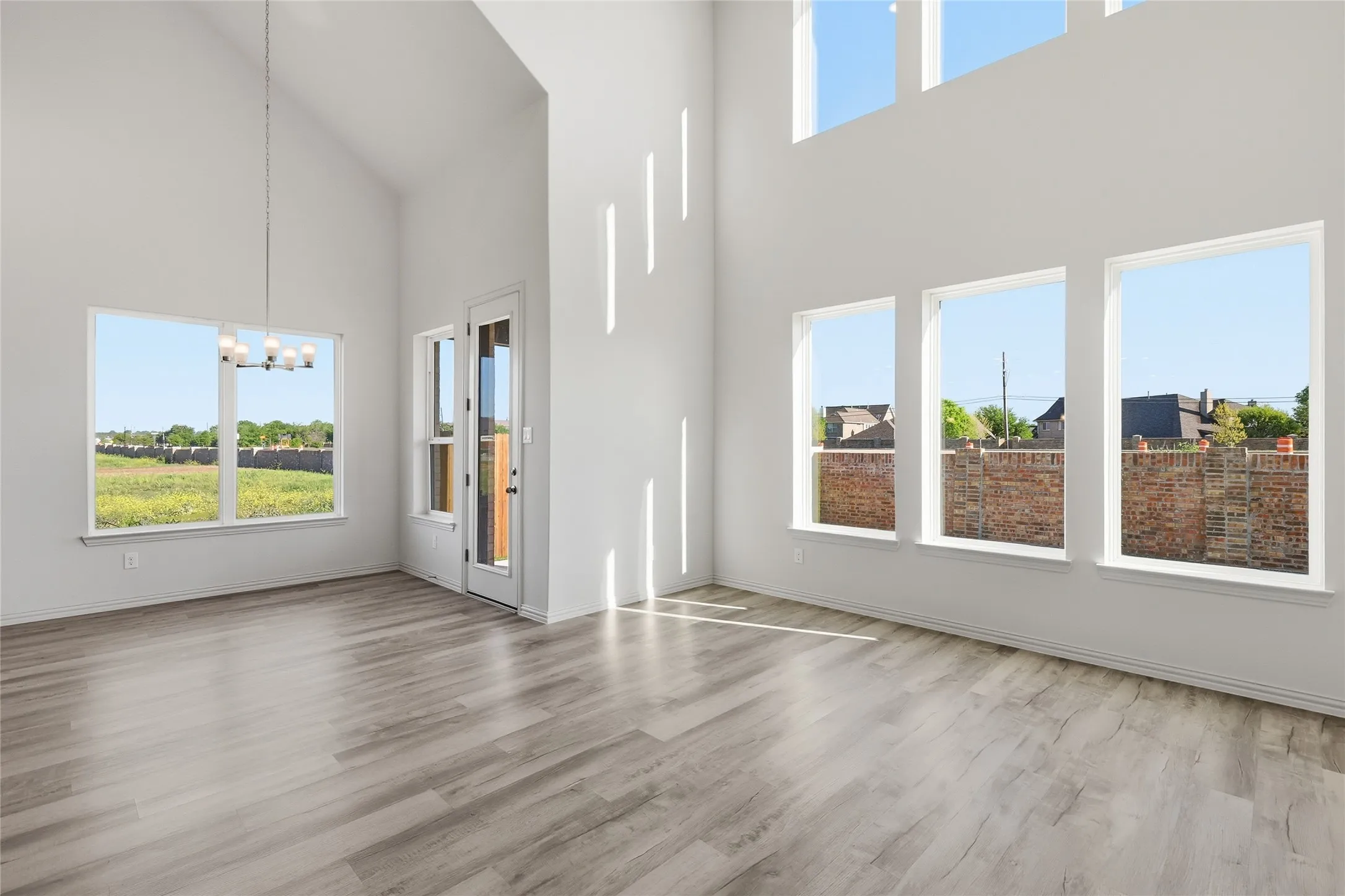 Unfurnished living room featuring a chandelier, light wood finished floors, and vaulted ceiling
