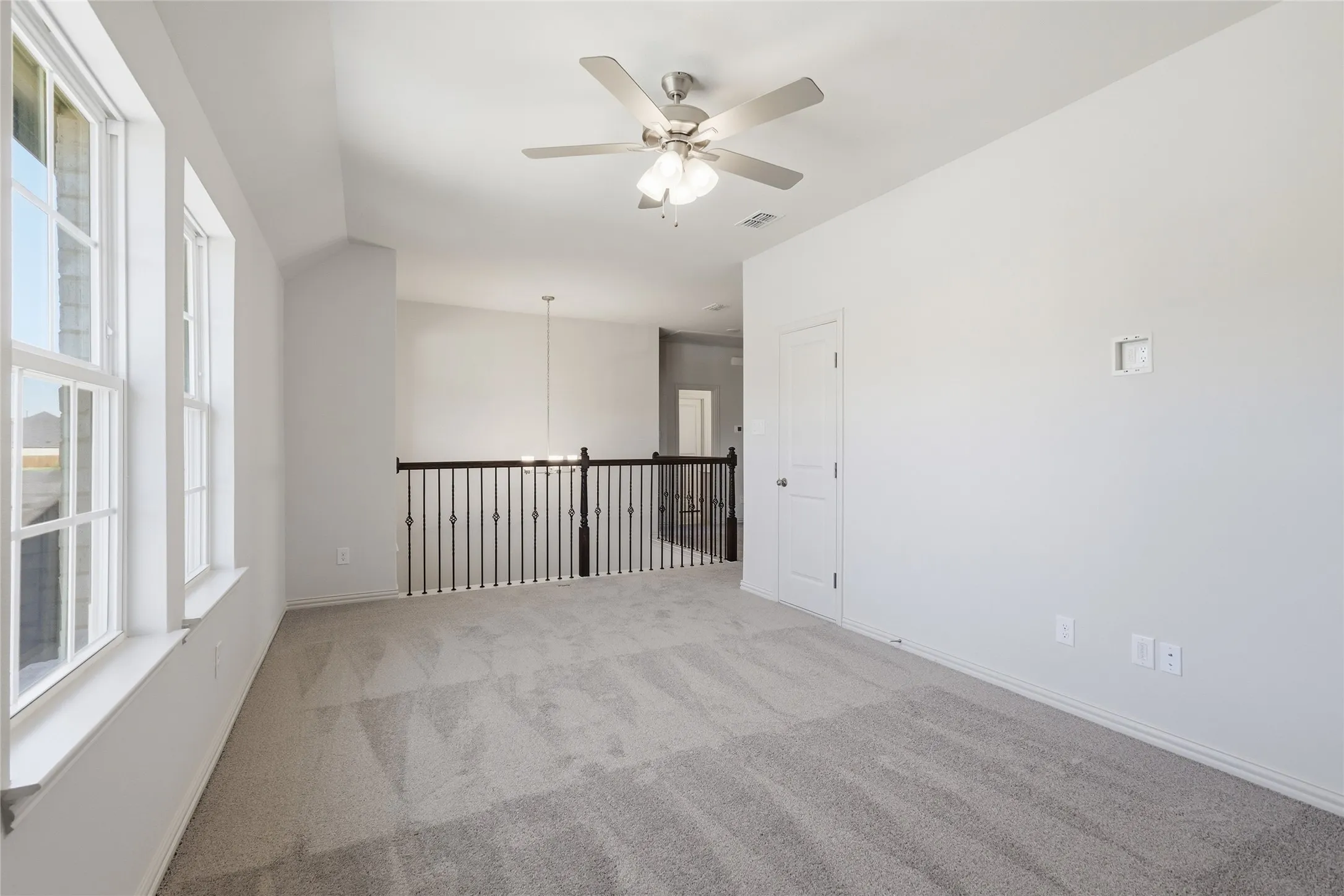Empty room featuring ceiling fan, light colored carpet, and vaulted ceiling