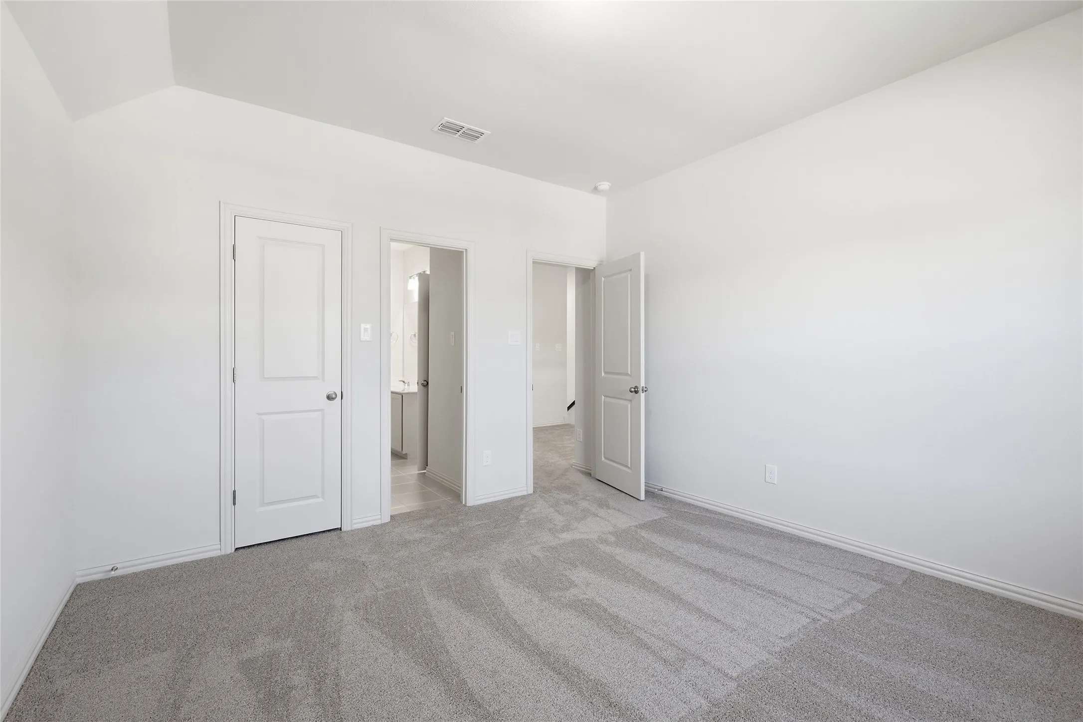 Unfurnished bedroom with light colored carpet and baseboards