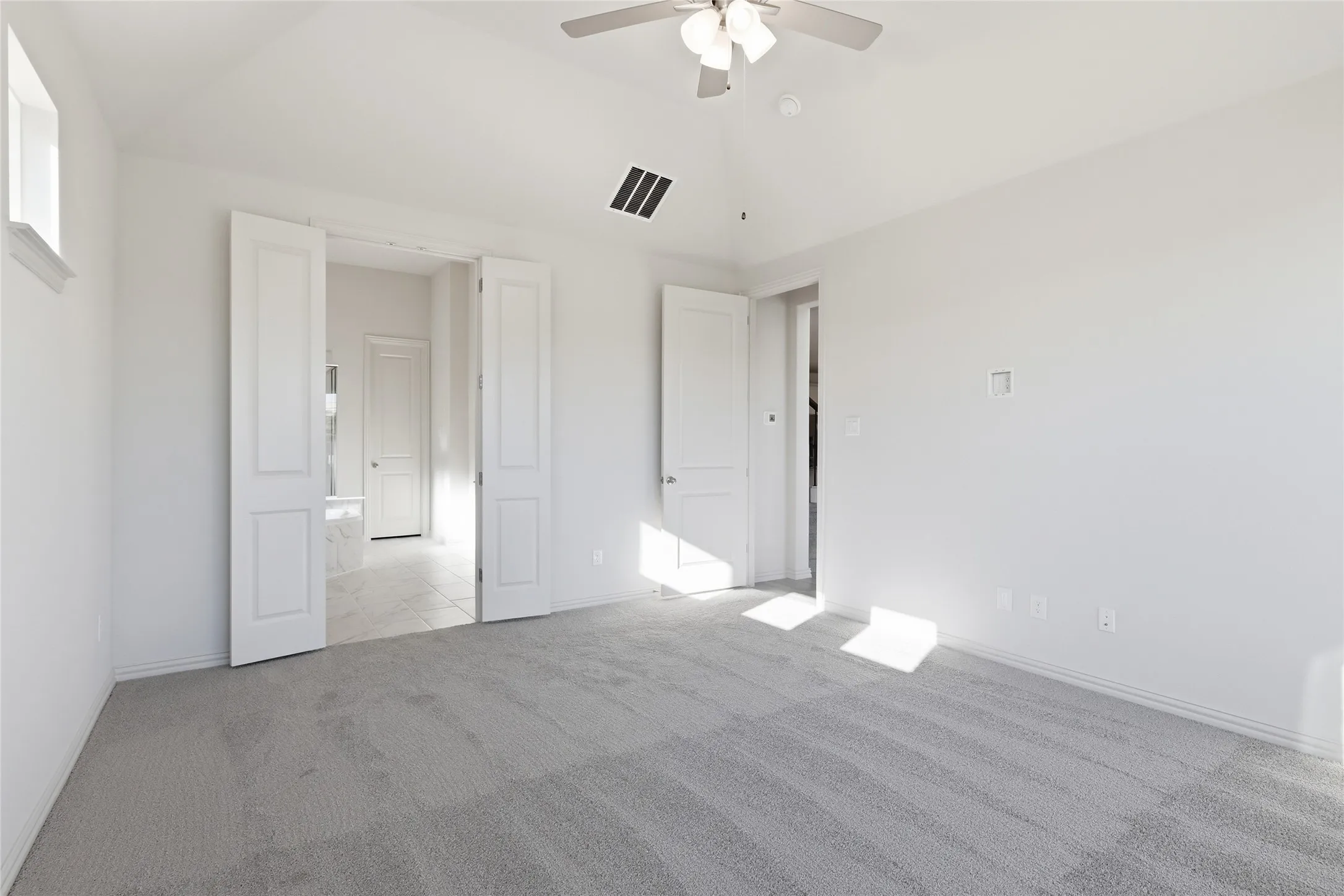 Unfurnished bedroom featuring light carpet, vaulted ceiling, and ceiling fan