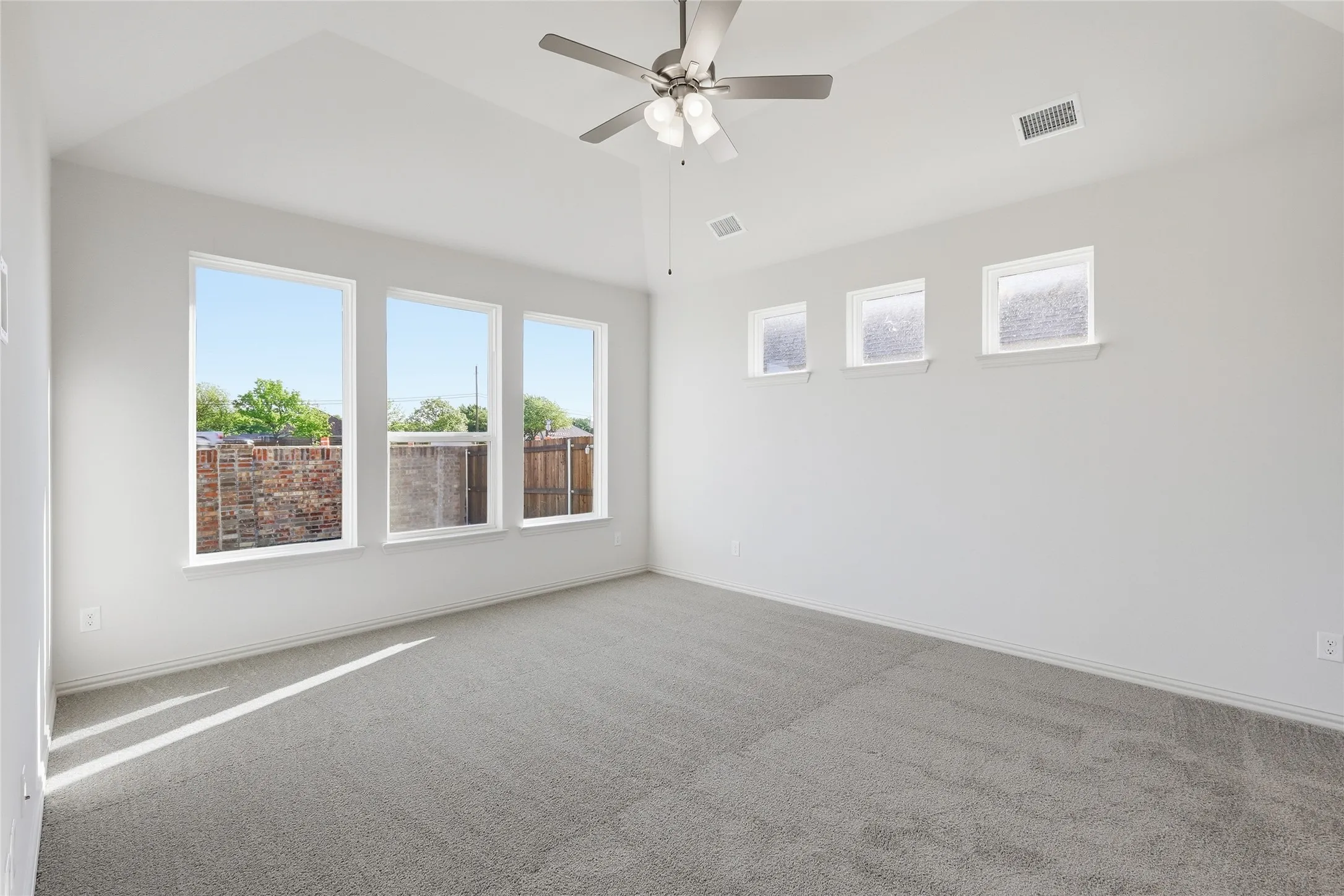 Empty room with ceiling fan, carpet flooring, and lofted ceiling