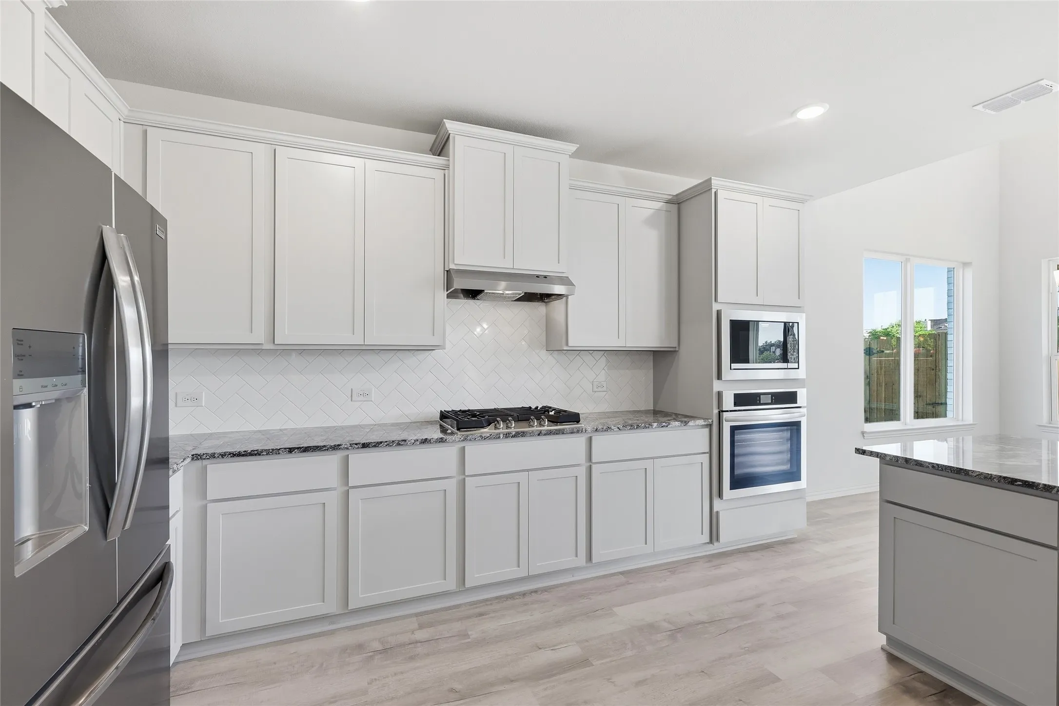 Kitchen featuring stainless steel appliances, light stone countertops, light wood-type flooring, recessed lighting, and white cabinets