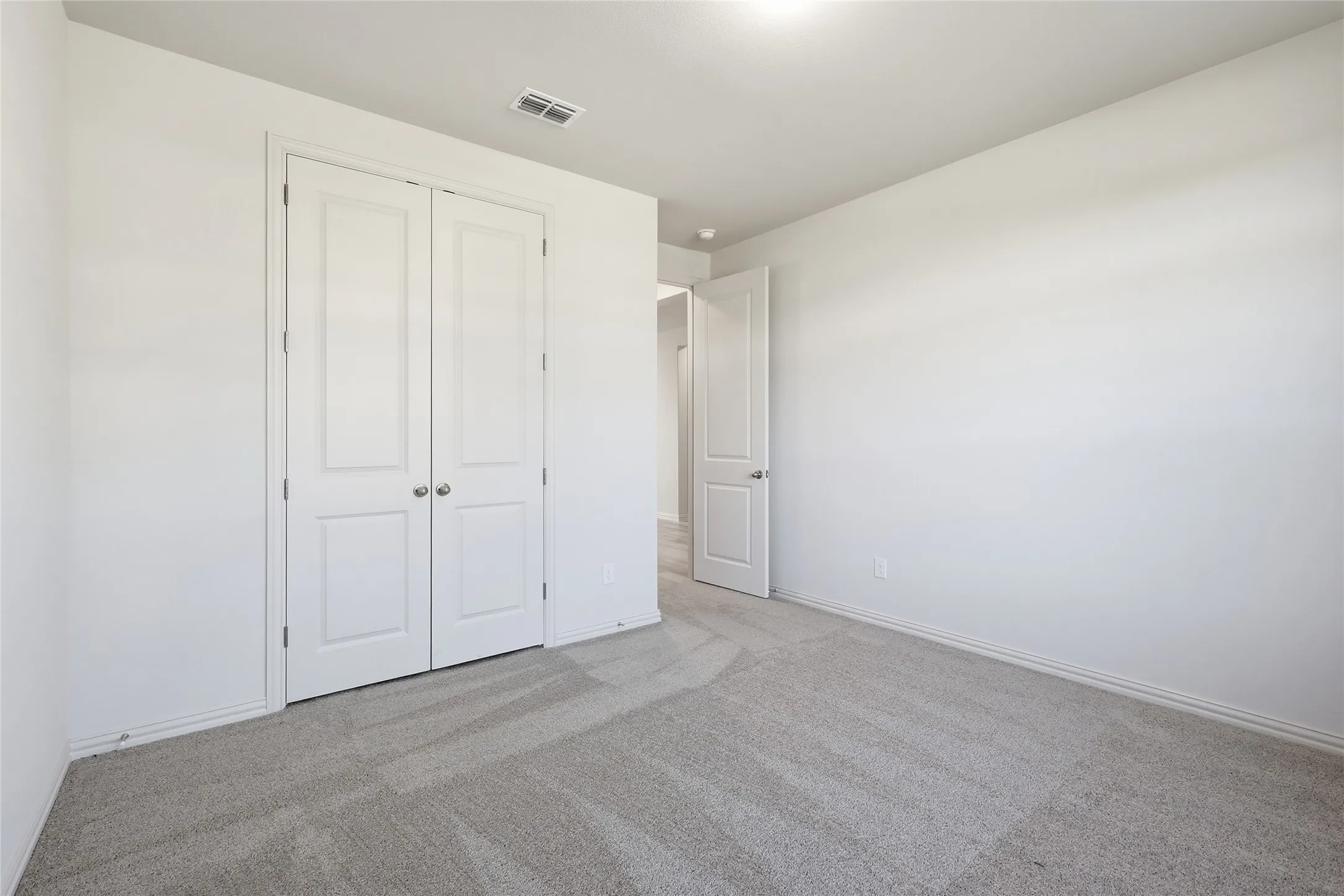 Unfurnished bedroom featuring light colored carpet and a closet
