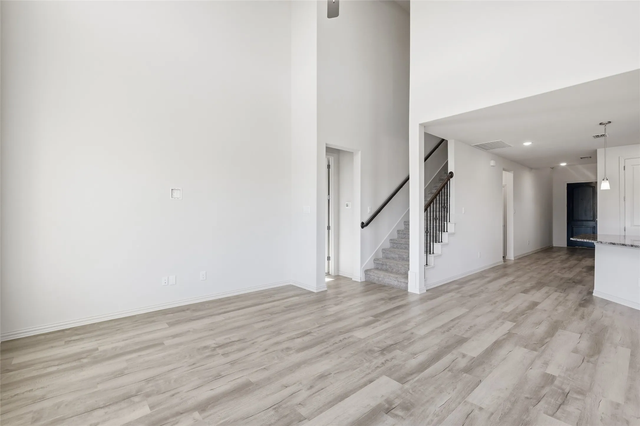 Unfurnished living room featuring a high ceiling, light wood-style floors, and recessed lighting