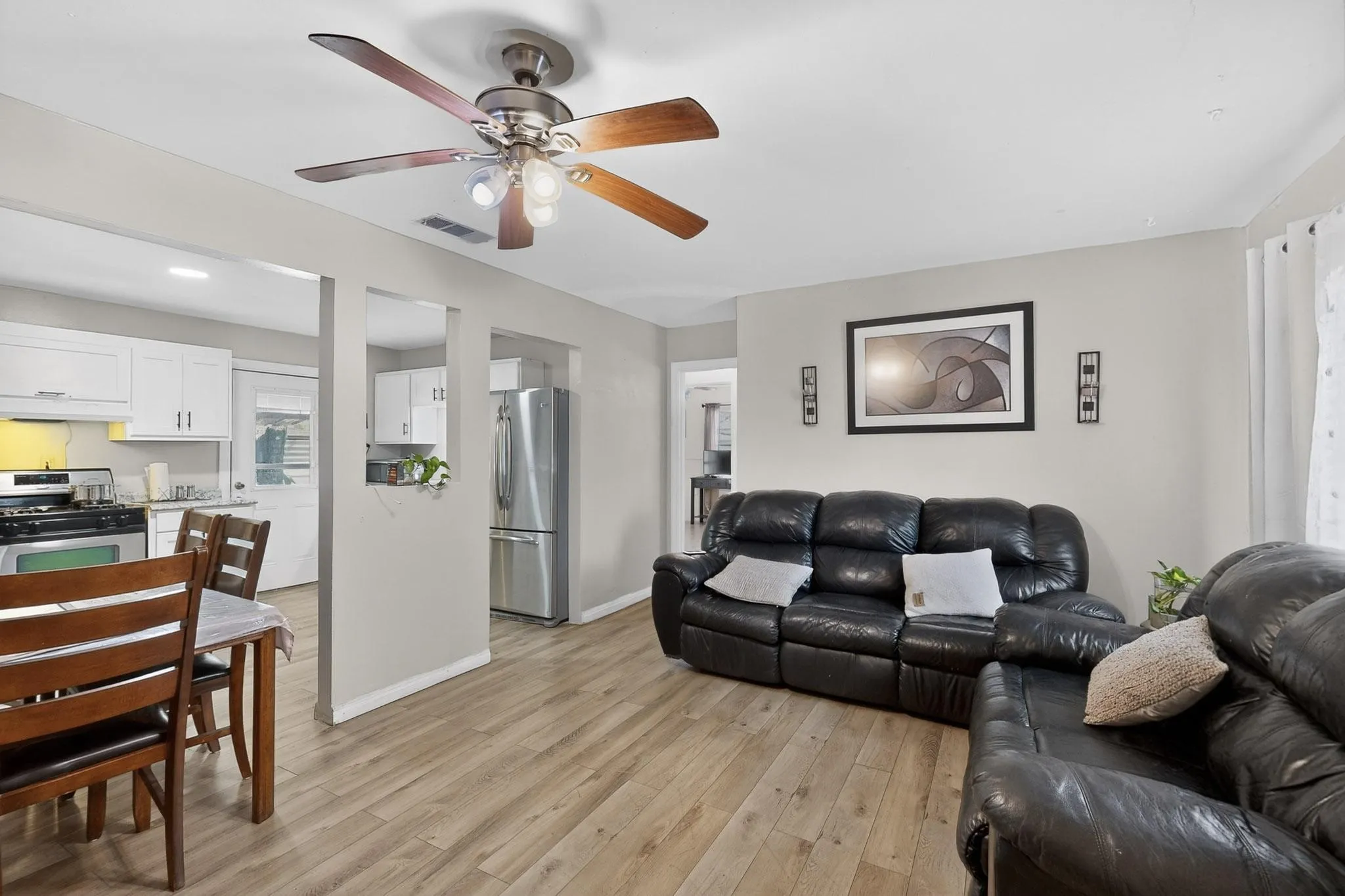 Living room with light wood-type flooring and a ceiling fan
