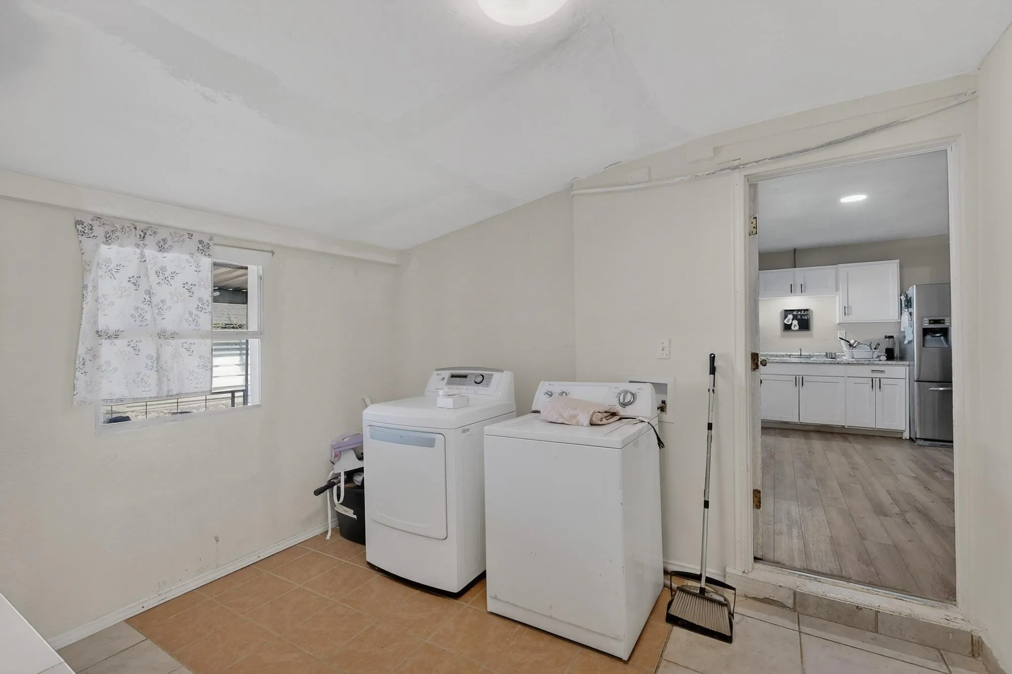 Laundry area featuring vaulted ceiling, separate washer and dryer, and light tile patterned flooring