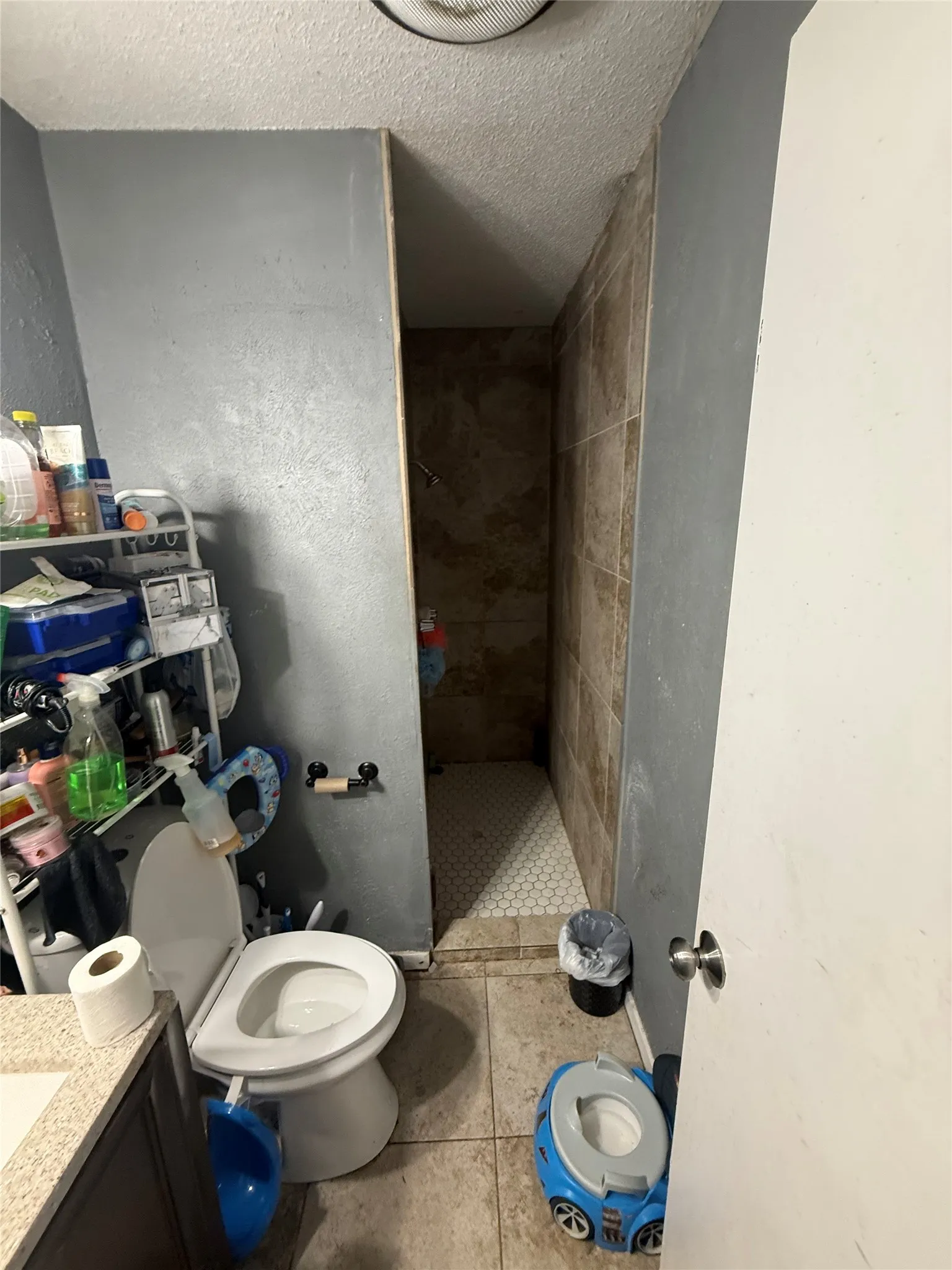 Full bathroom with a textured ceiling, vanity, a shower stall, and light tile patterned flooring