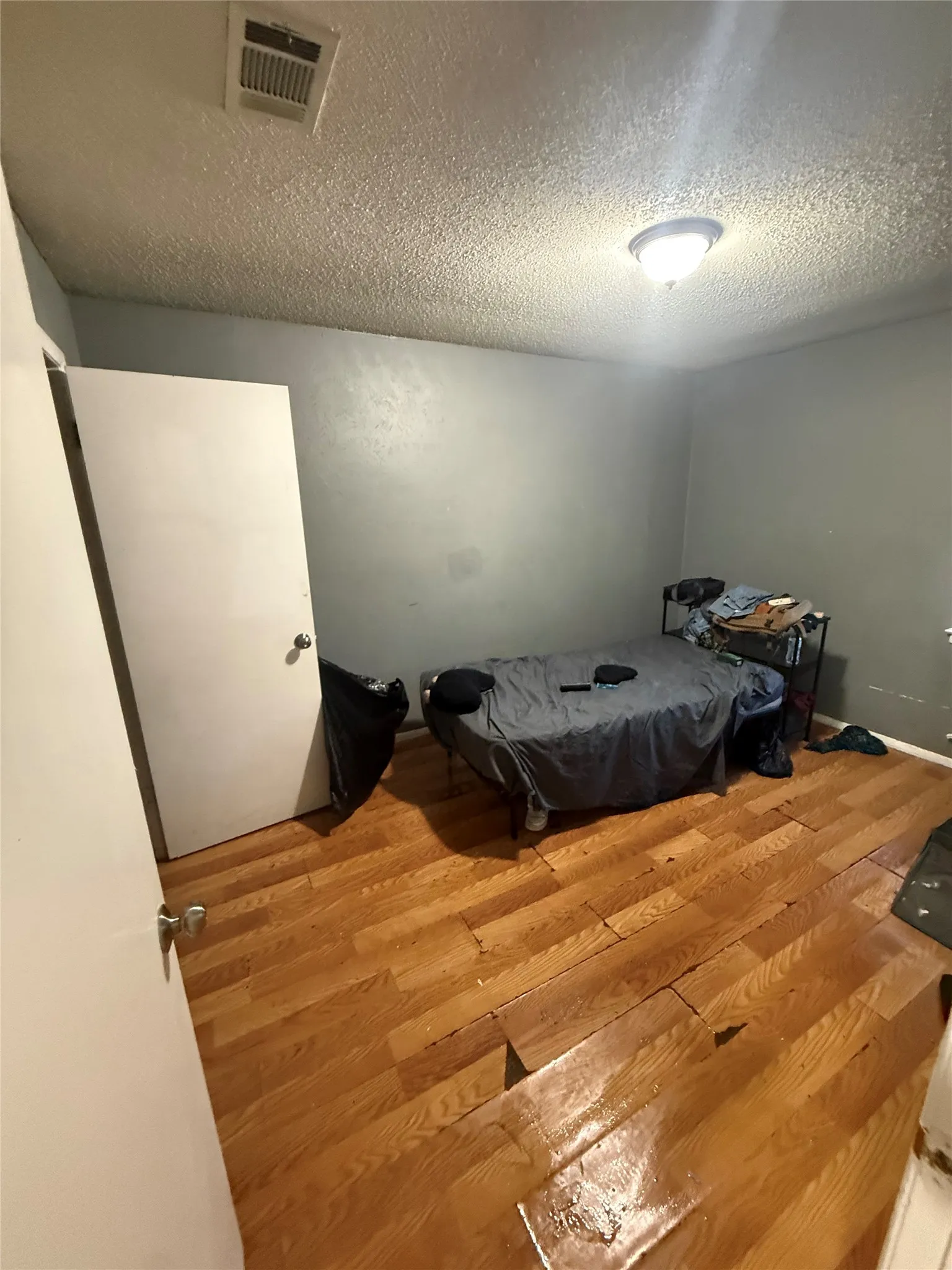 Bedroom with a textured ceiling and wood finished floors