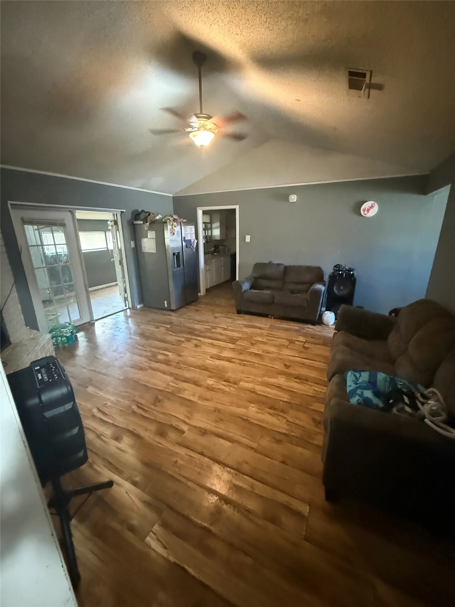Living area featuring wood finished floors, a ceiling fan, and a textured ceiling