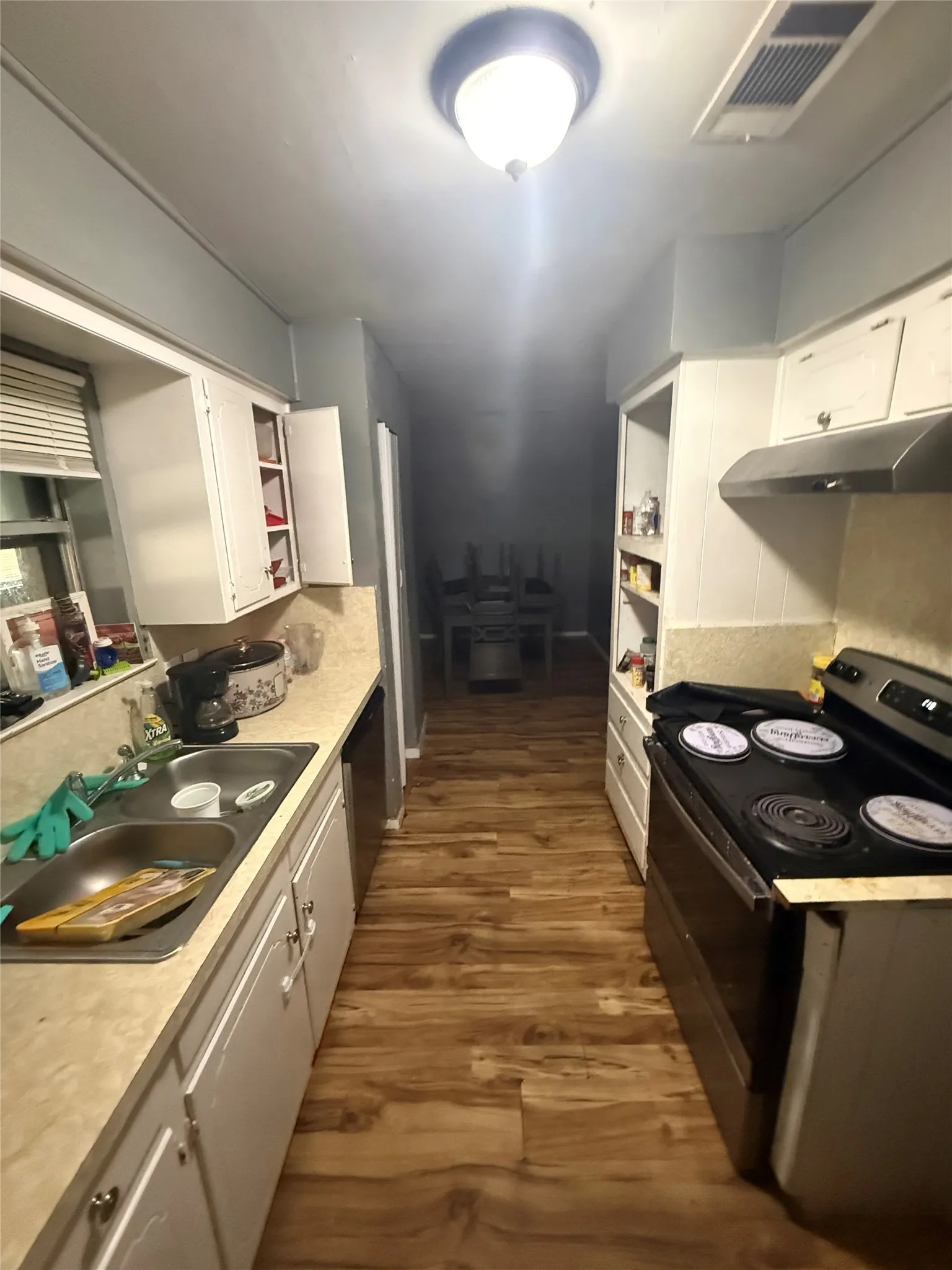 Kitchen with black appliances, white cabinets, open shelves, and dark wood-type flooring