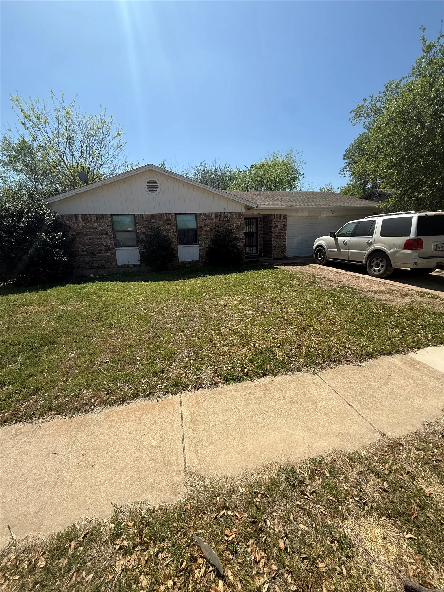 View of front facade featuring brick siding, an attached garage, and a front yard