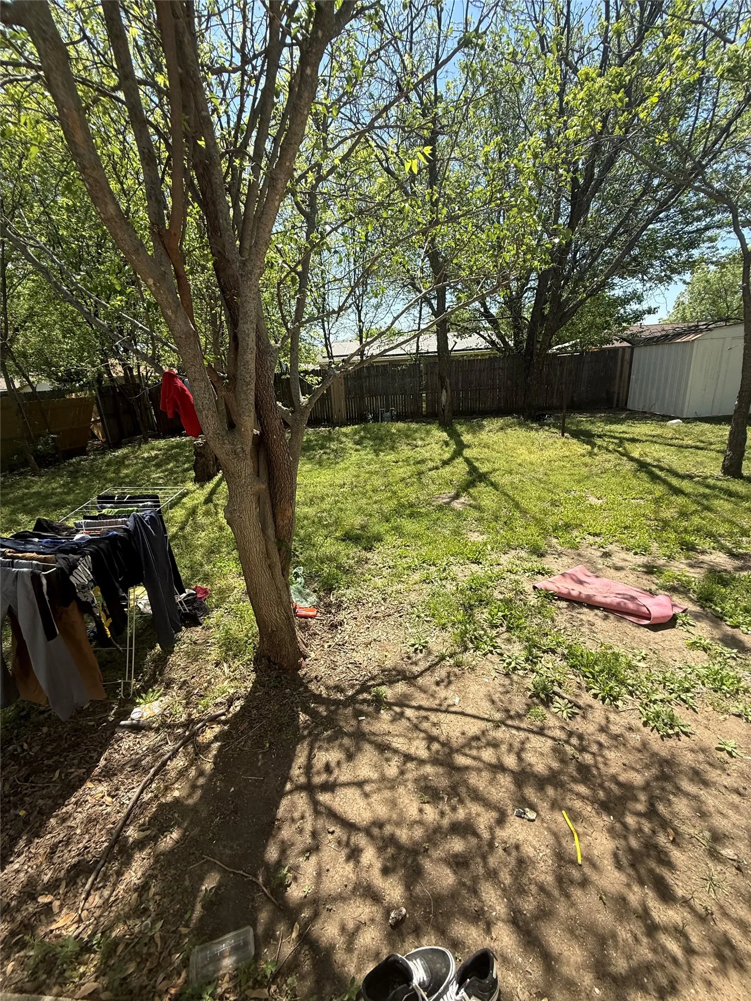 Fenced backyard featuring a storage unit