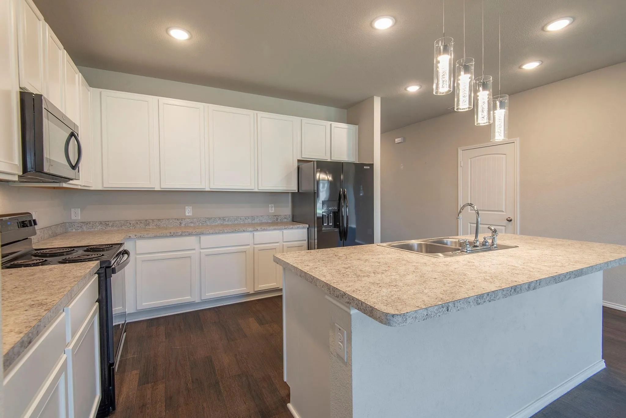 Kitchen featuring white cabinetry, light-colored countertops, stainless steel sink, dark wood-finish flooring, and pendant lighting
