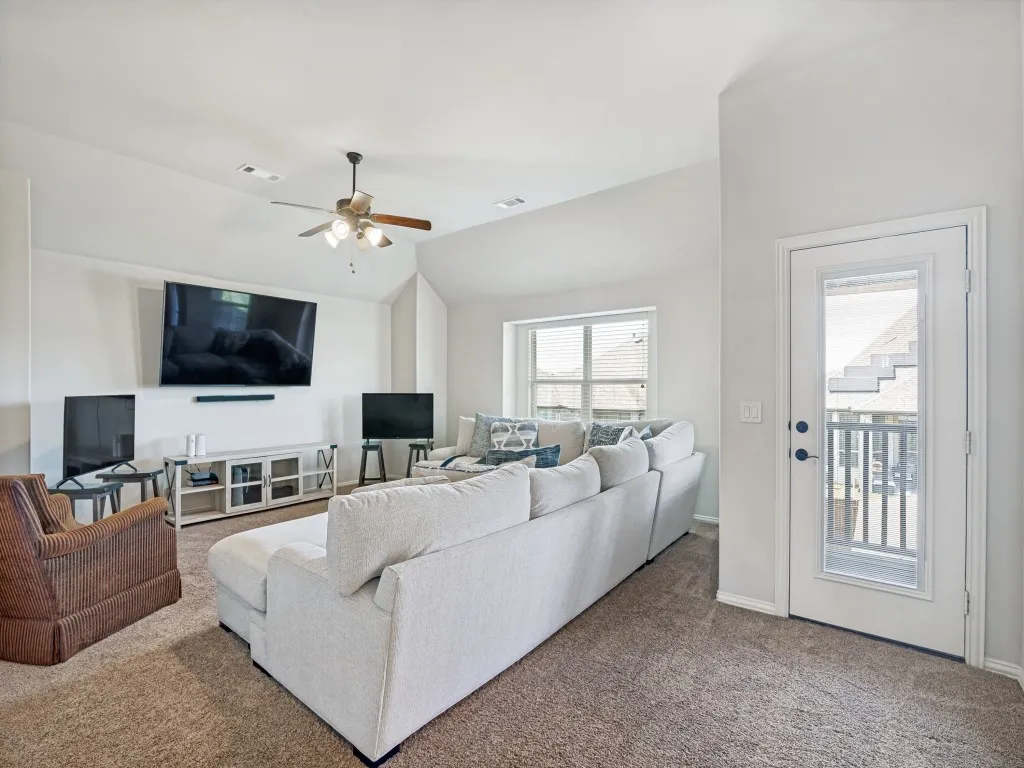 Living room featuring carpet, ceiling fan, and lofted ceiling