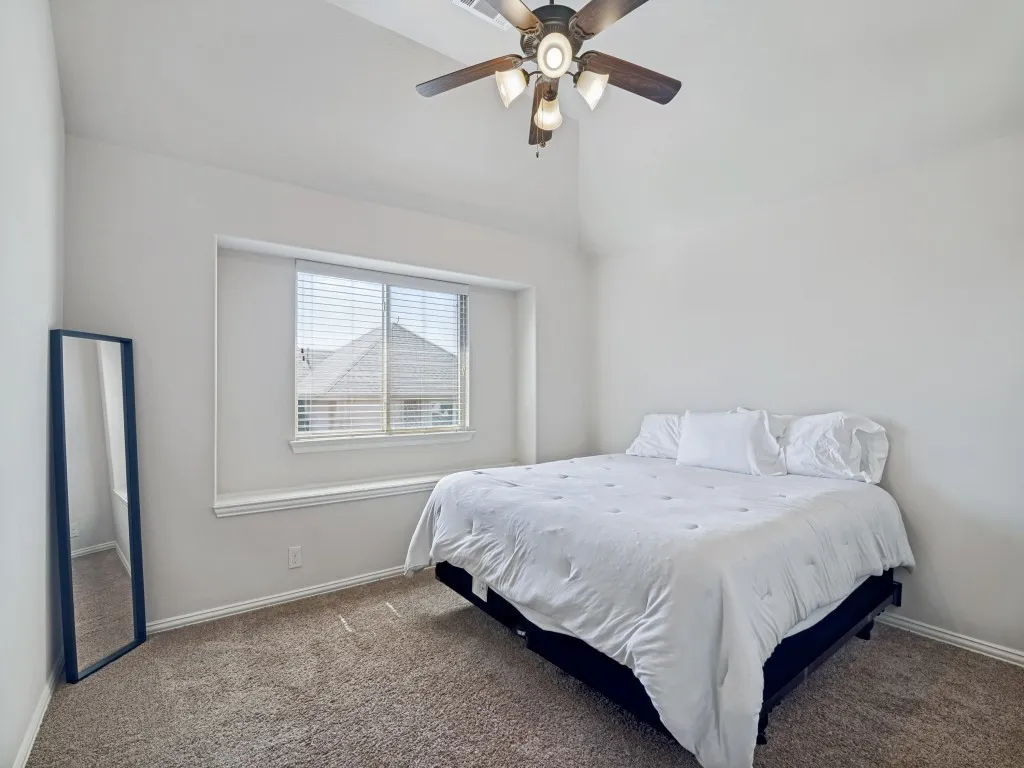 Bedroom with carpet flooring, ceiling fan, and vaulted ceiling
