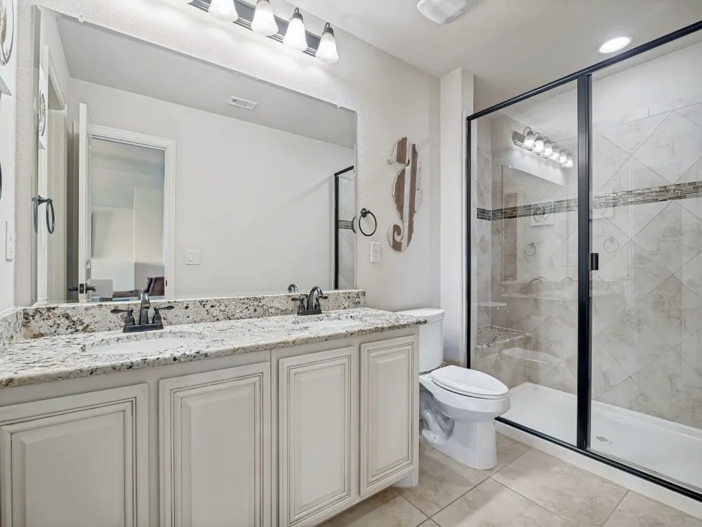 Full bathroom with double vanity, a stall shower, and light tile patterned floors