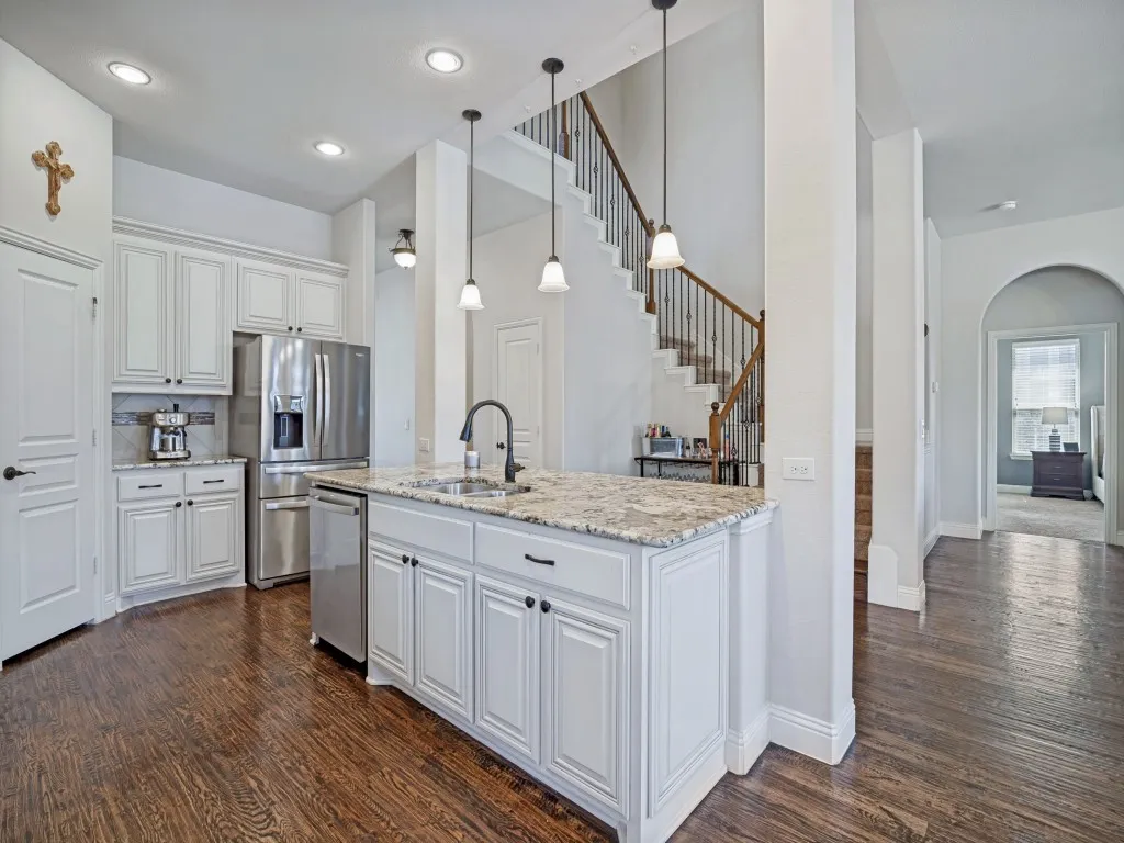 Kitchen with white cabinetry, stainless steel appliances, dark wood-style flooring, and light stone countertops