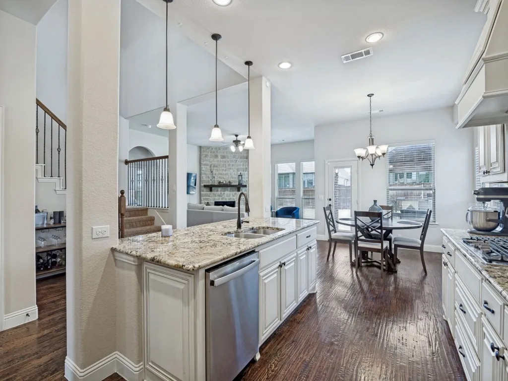 Kitchen featuring dark wood finished floors, a large fireplace, stainless steel appliances, and light stone countertops