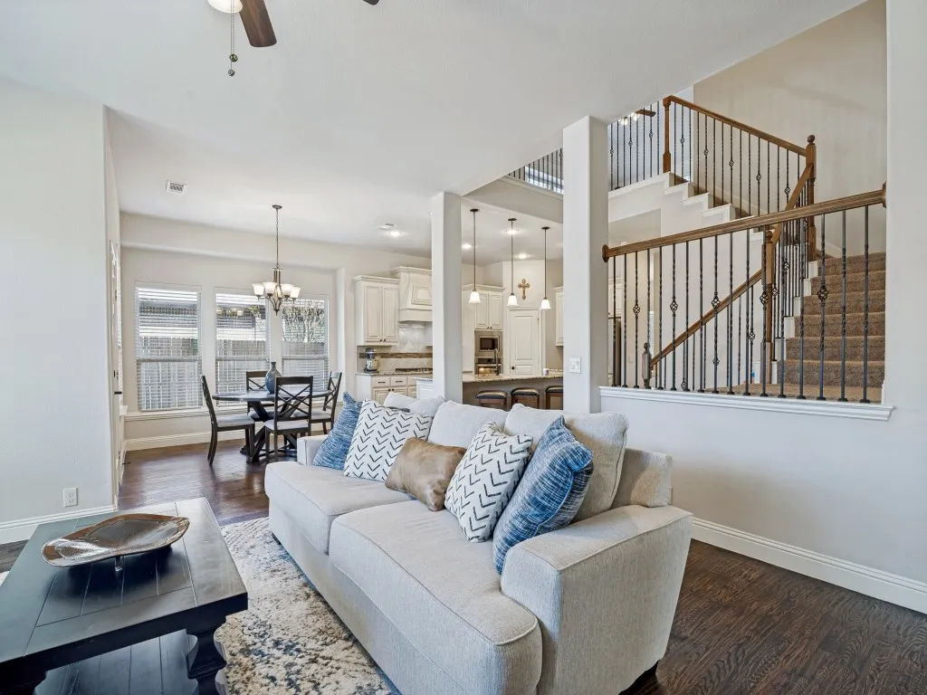Living area with dark wood-type flooring, a ceiling fan, and hanging lights