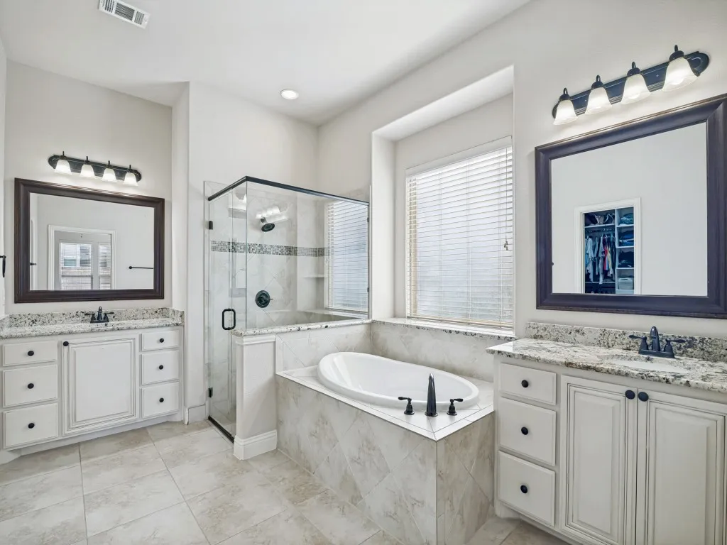 Bathroom with a shower stall, two vanities, a garden tub, and light tile patterned floors