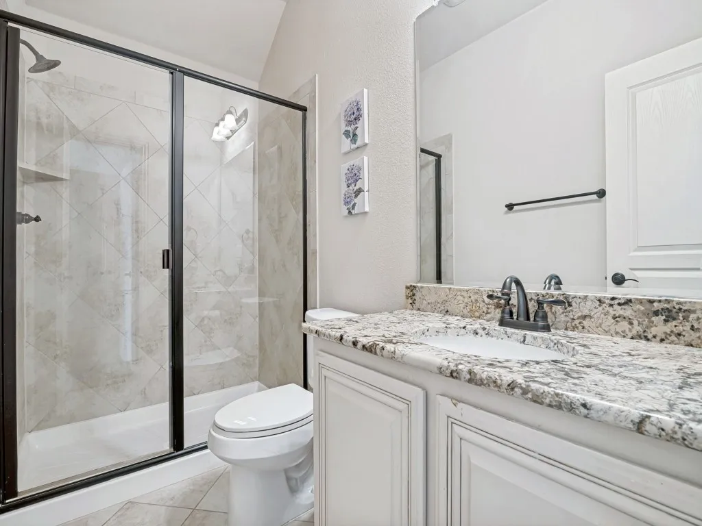 Bathroom featuring vanity, a shower stall, a textured wall, and light tile patterned flooring