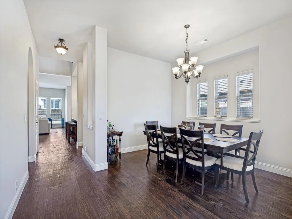 Dining area featuring dark wood finished floors, plenty of natural light, a chandelier, and arched walkways
