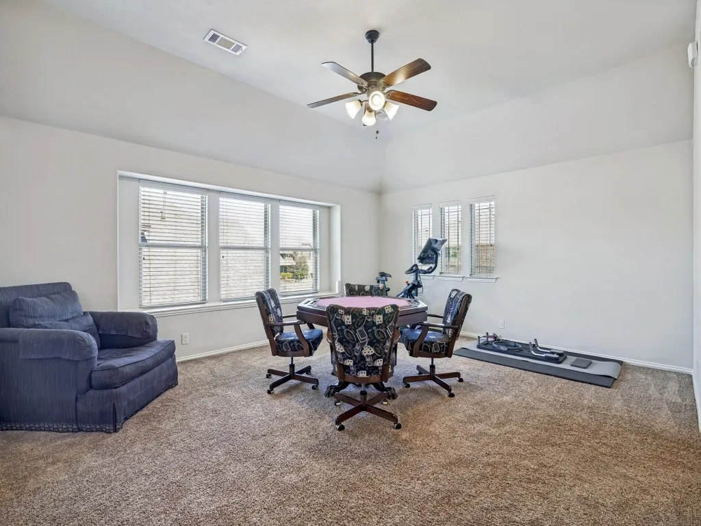 Home office with carpet flooring, a ceiling fan, and lofted ceiling