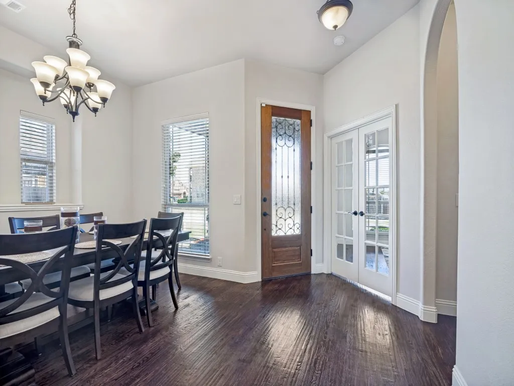 Foyer featuring dark wood-style floors, french doors, and a chandelier