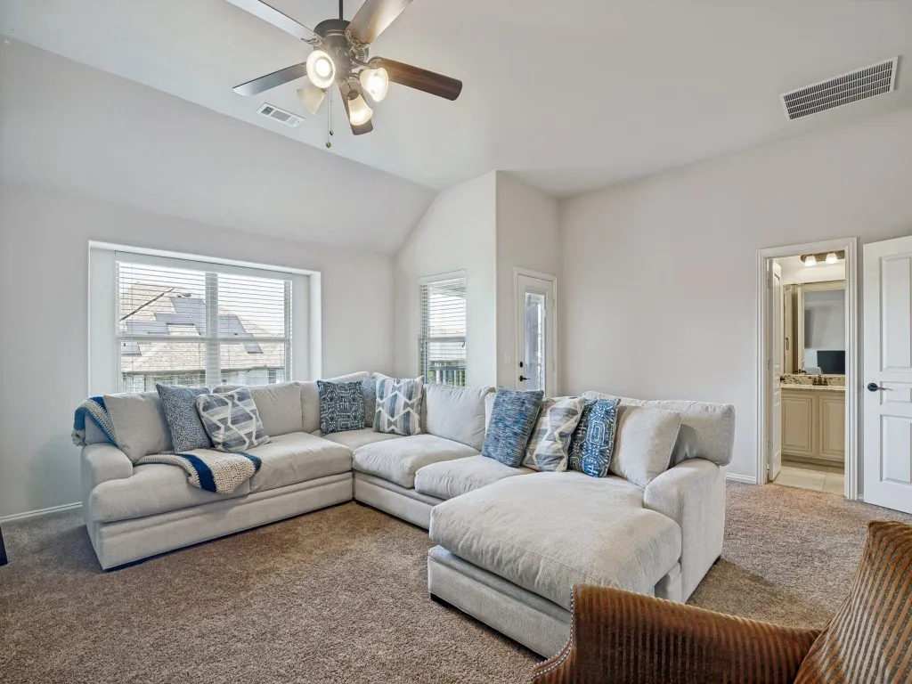 Carpeted living room featuring ceiling fan, plenty of natural light, and vaulted ceiling