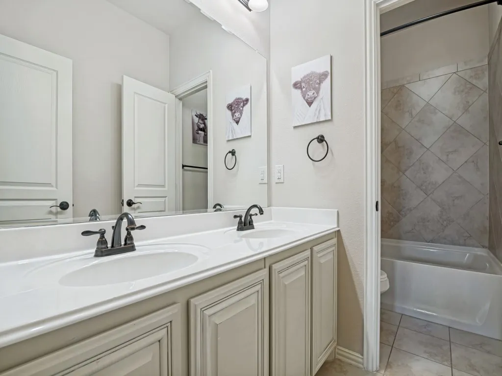 Bathroom featuring double vanity,  shower combination, and light tile patterned flooring