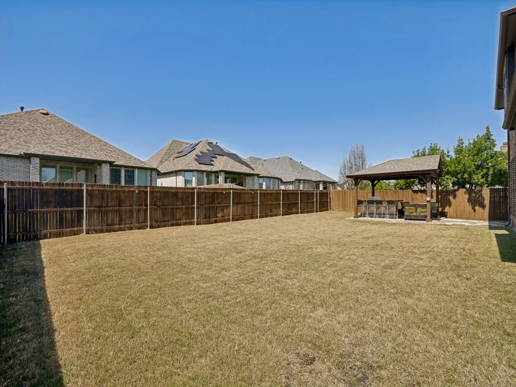 Fenced backyard featuring a patio, a residential view, and a gazebo