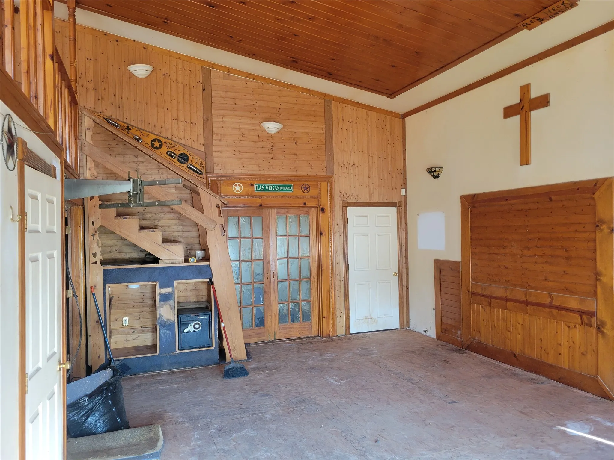Unfurnished living room featuring wooden walls, french doors, and a vaulted wood ceiling