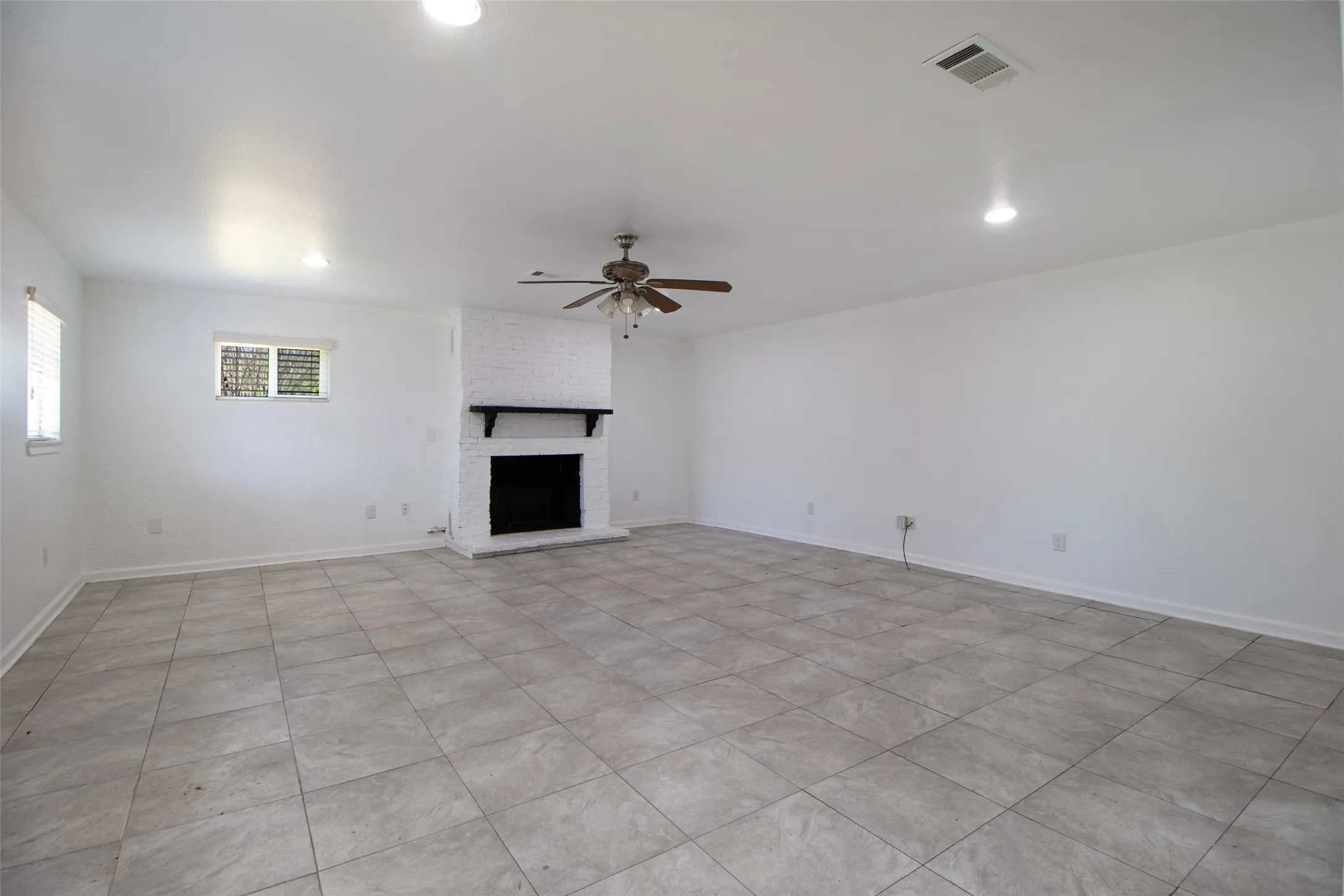Living room featuring a ceiling fan, a brick fireplace, recessed lighting, and light tile patterned flooring