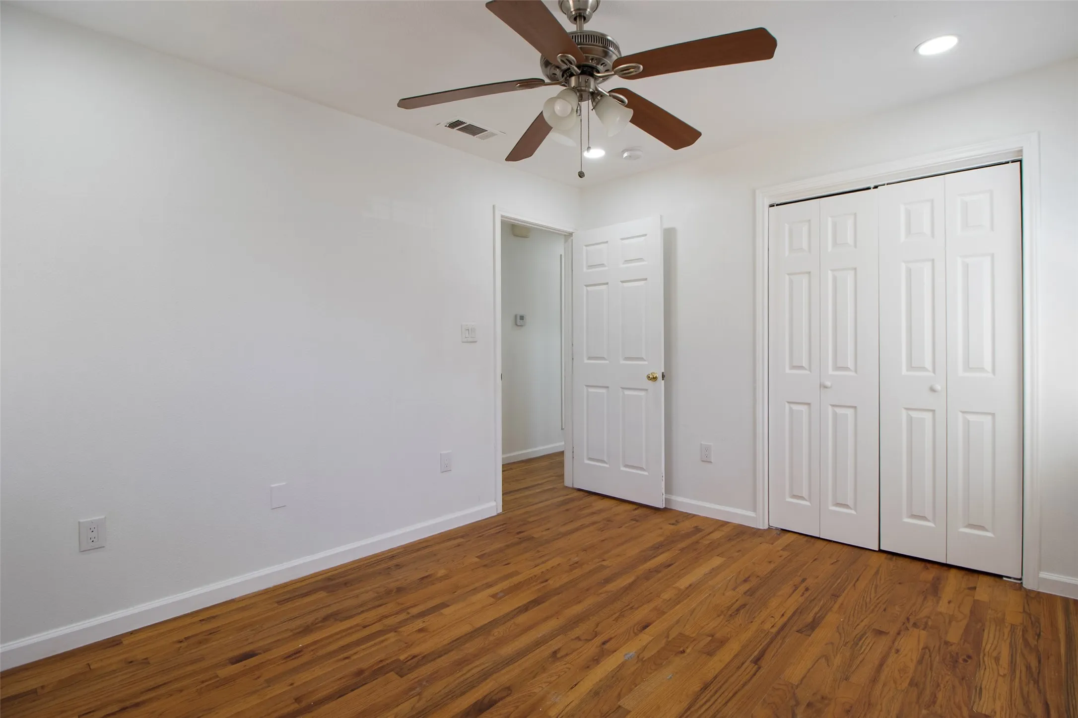 Bedroom with wood flooring, a ceiling fan, and recessed lighting