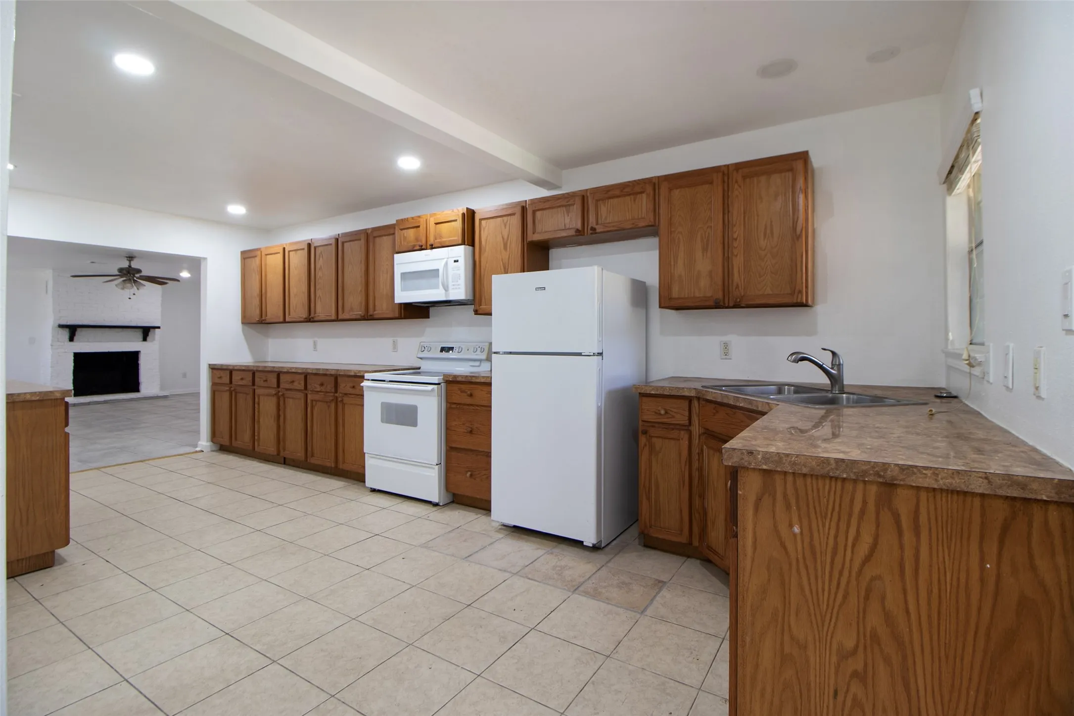 Kitchen featuring wood finish cabinetry, white appliances and recessed lighting.