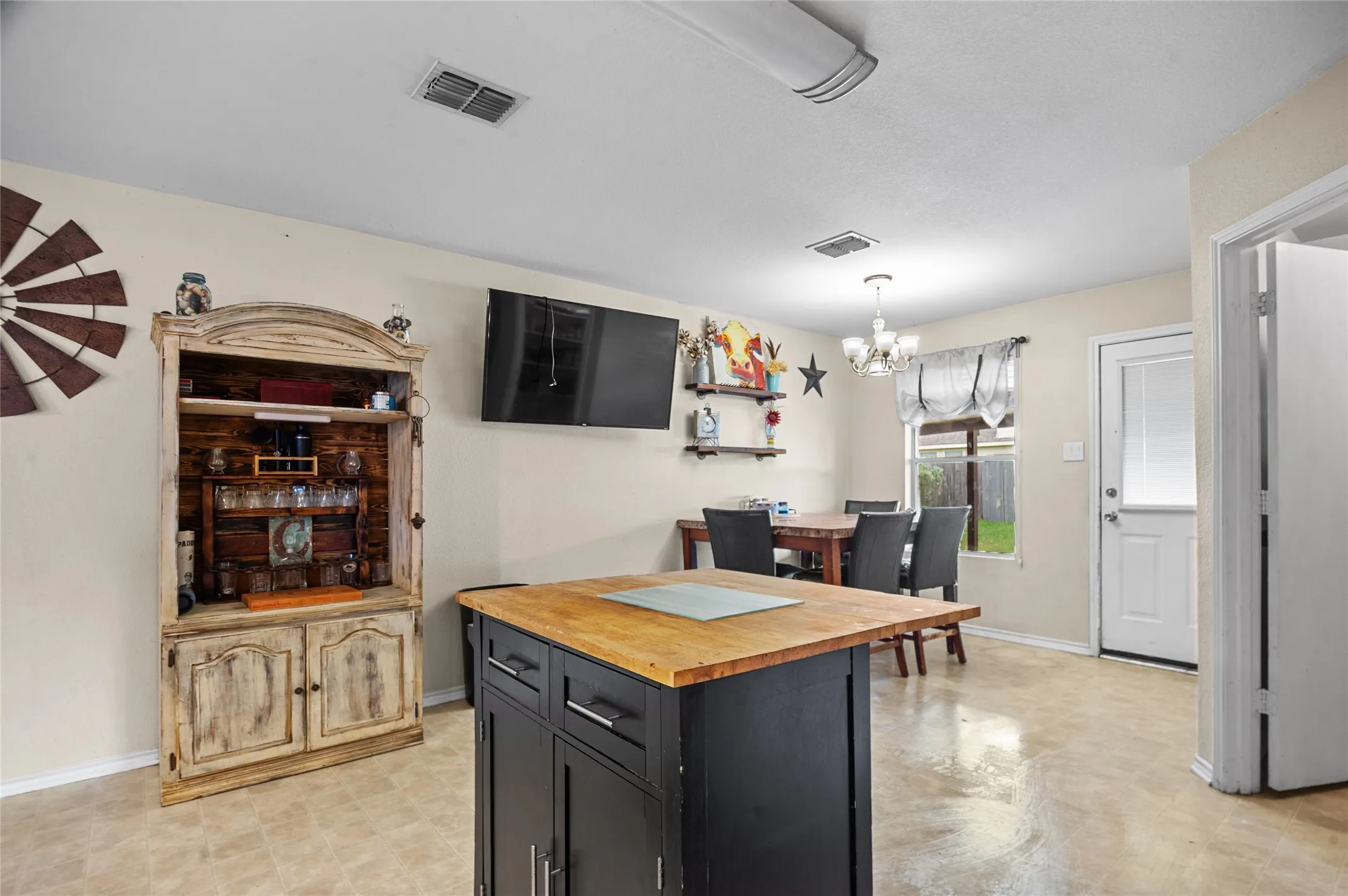 Kitchen featuring wooden counters, a chandelier, dark cabinets, and decorative light fixtures