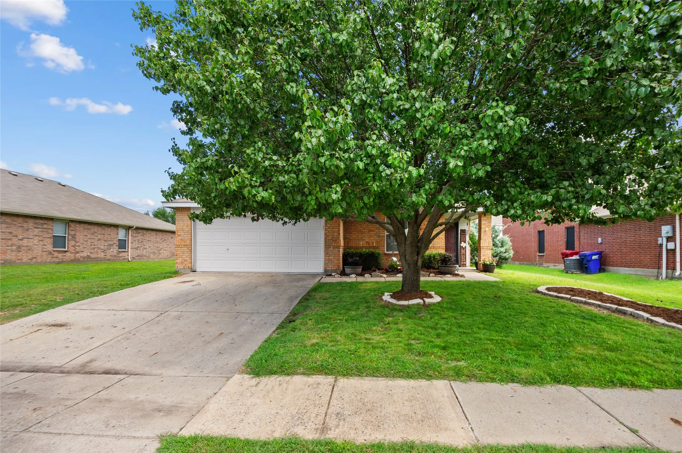 Obstructed view of property with concrete driveway, brick siding, a garage, and a front yard