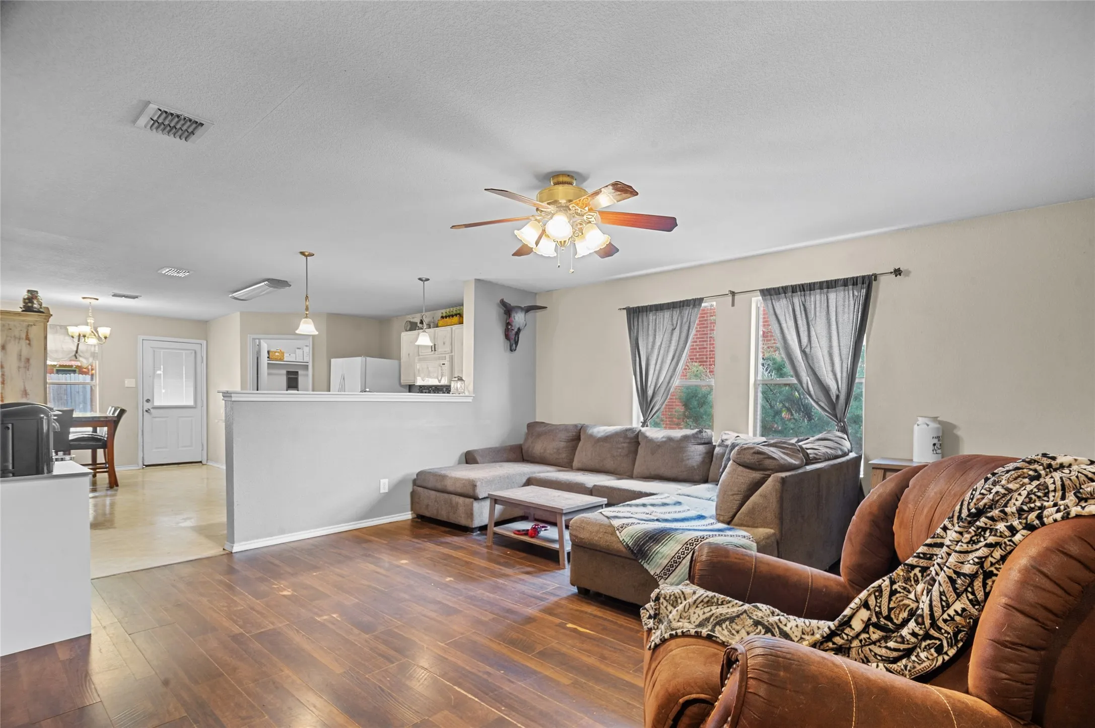 Living room featuring a ceiling fan, healthy amount of natural light, a chandelier, and wood finished floors