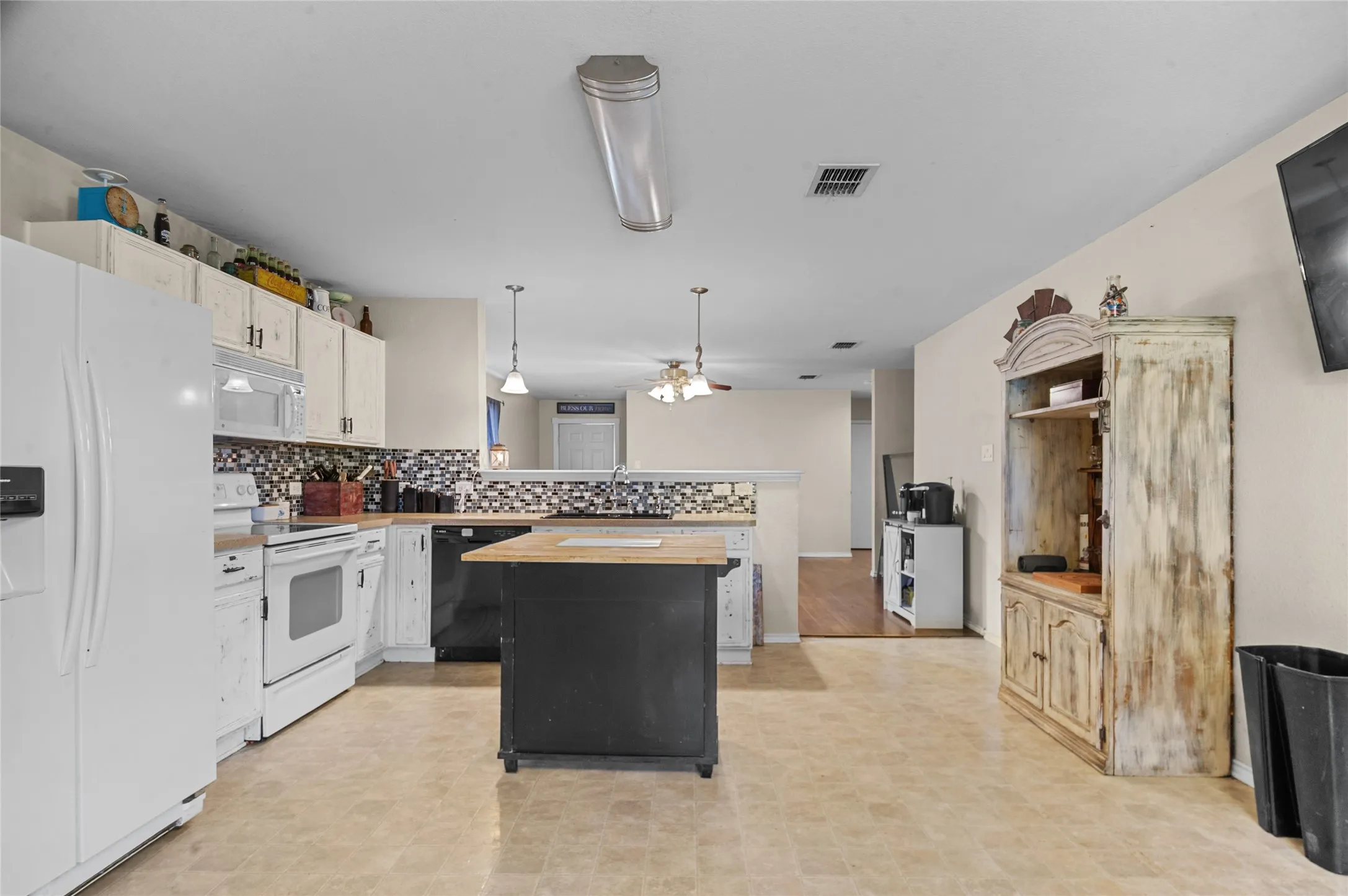 Kitchen with white appliances, butcher block countertops, a peninsula, backsplash, and a kitchen island
