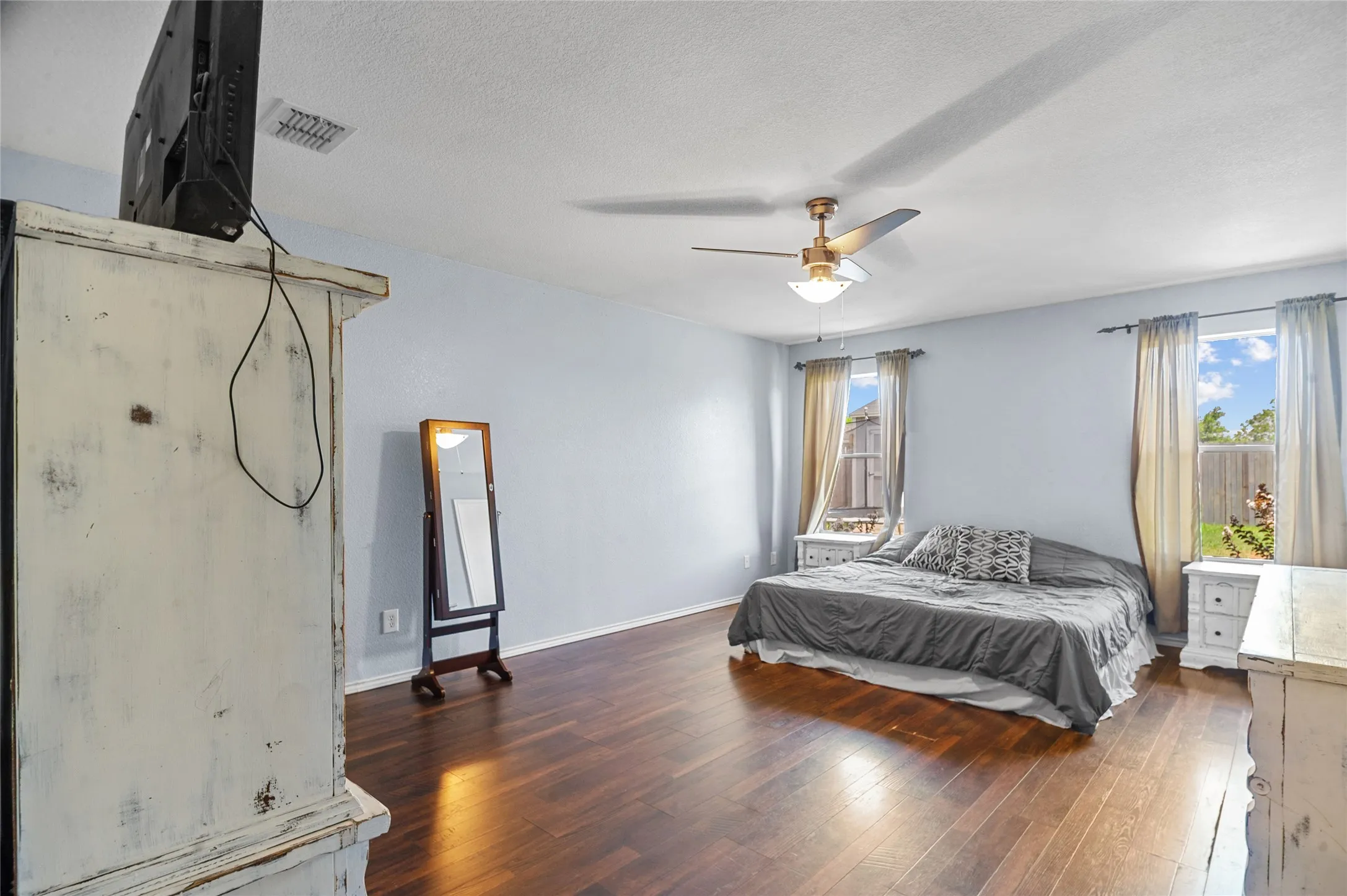 Bedroom with wood finished floors, a textured ceiling, and a ceiling fan