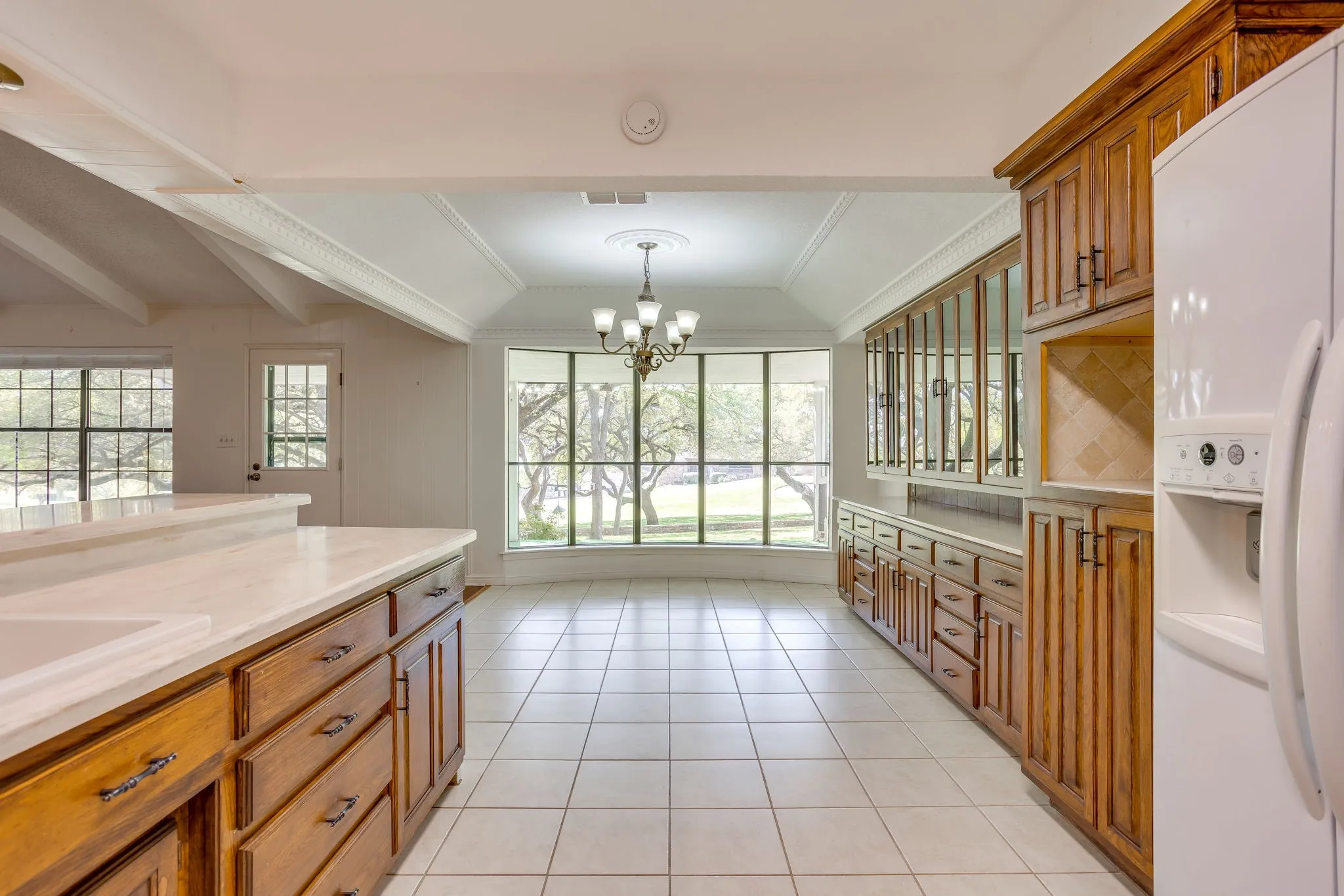 Kitchen features a large number of cabinets, great countertops with backsplash, built-in china cabinet, dine-in area with bay window featuring a great view of the golf course.