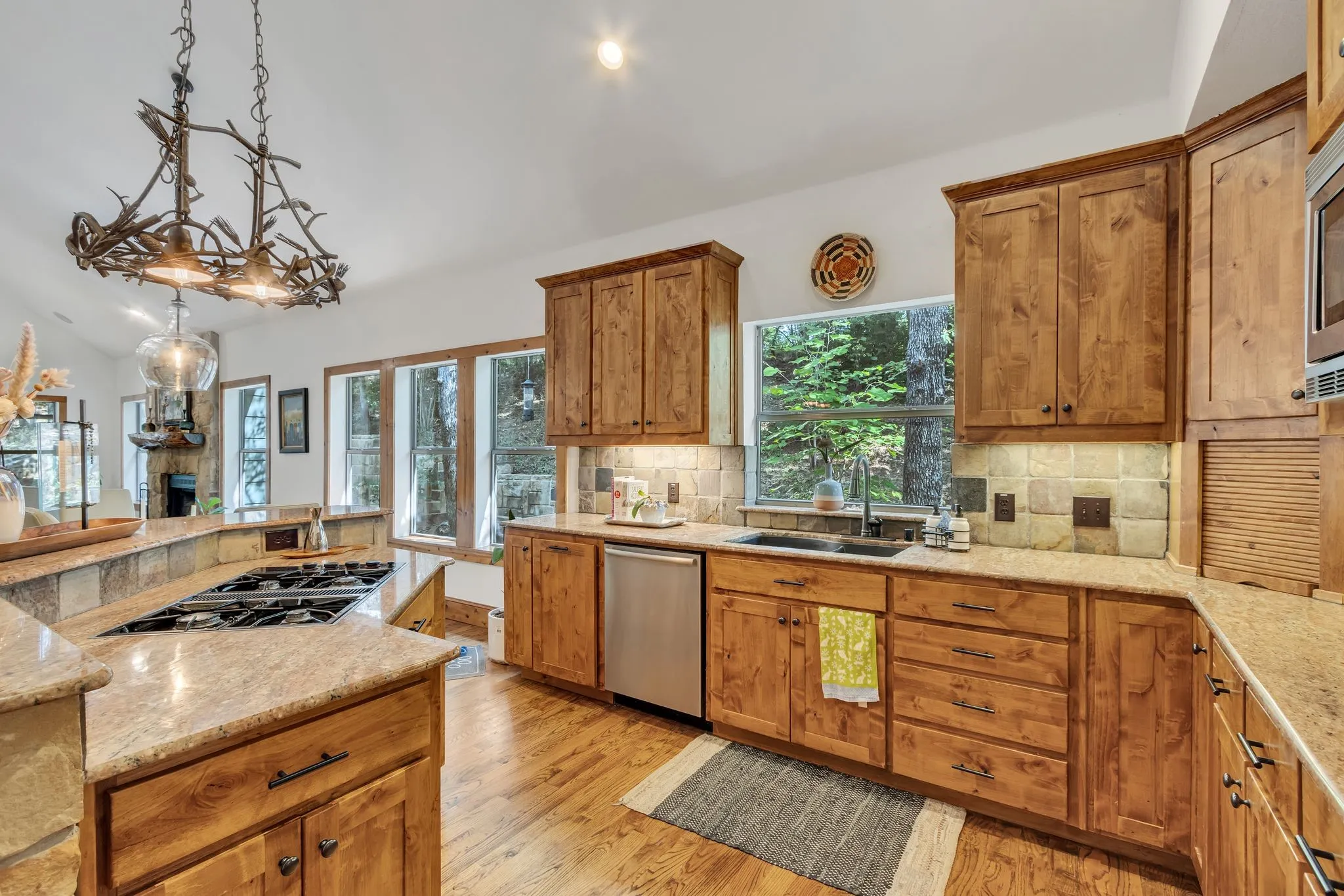 Kitchen featuring natural wood cabinetry, light-toned granite countertops, and a stone tile backsplash
