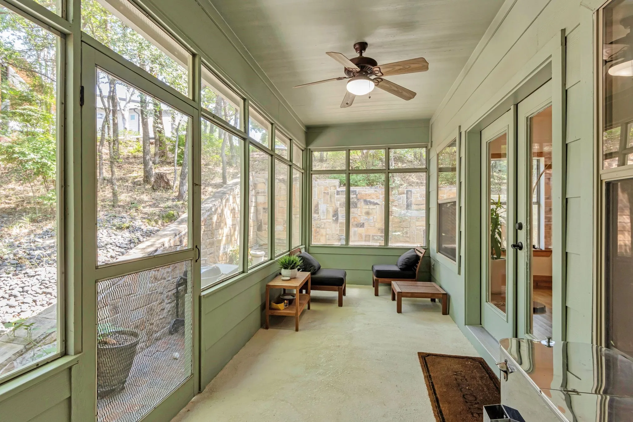 Screened porch featuring a ceiling fan with integrated lighting, shiplap wall paneling, and multiple glass-paned doors