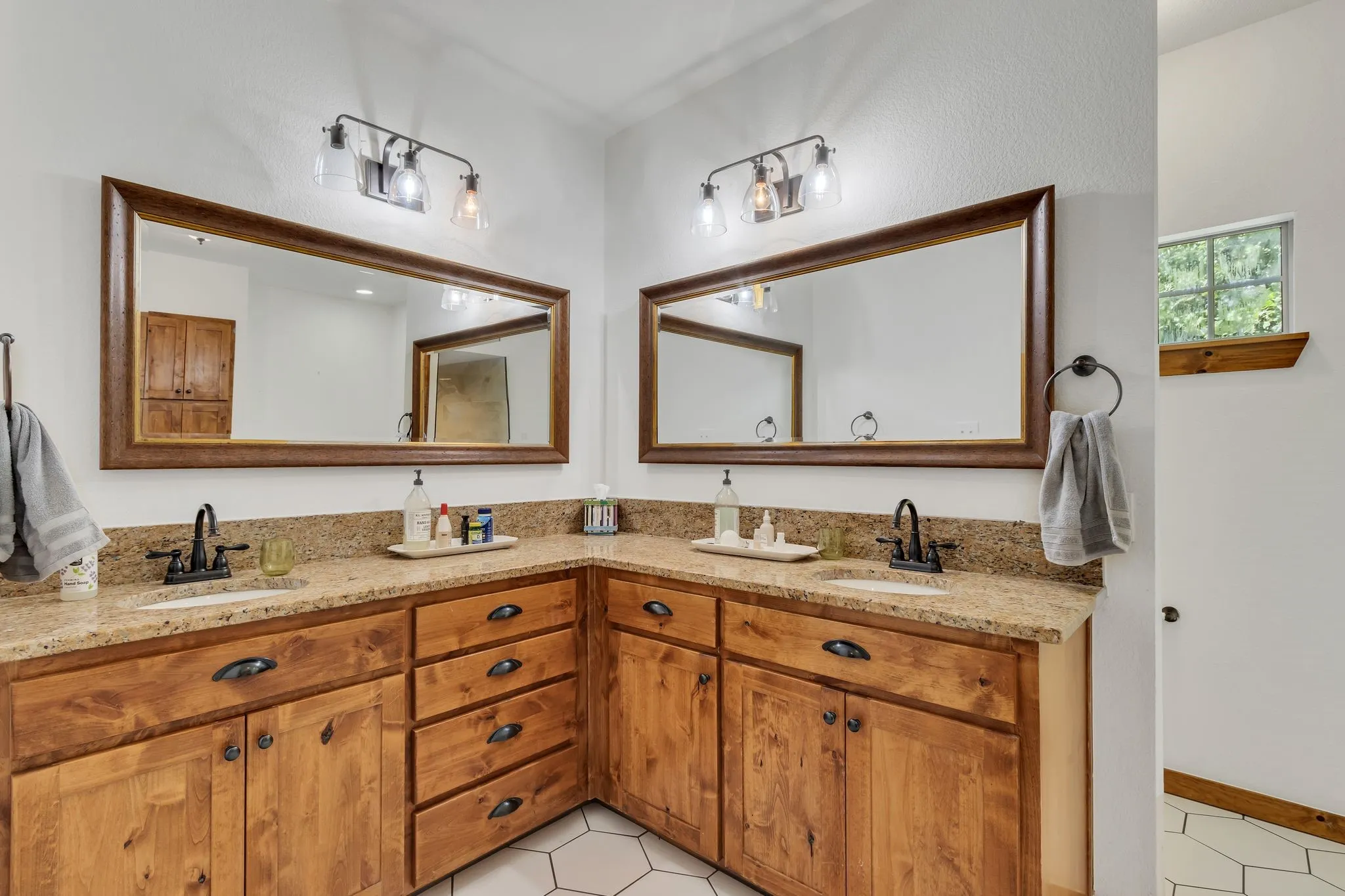 Dual vanity featuring rich wood-finish cabinetry, speckled countertops, and individual framed mirrors
