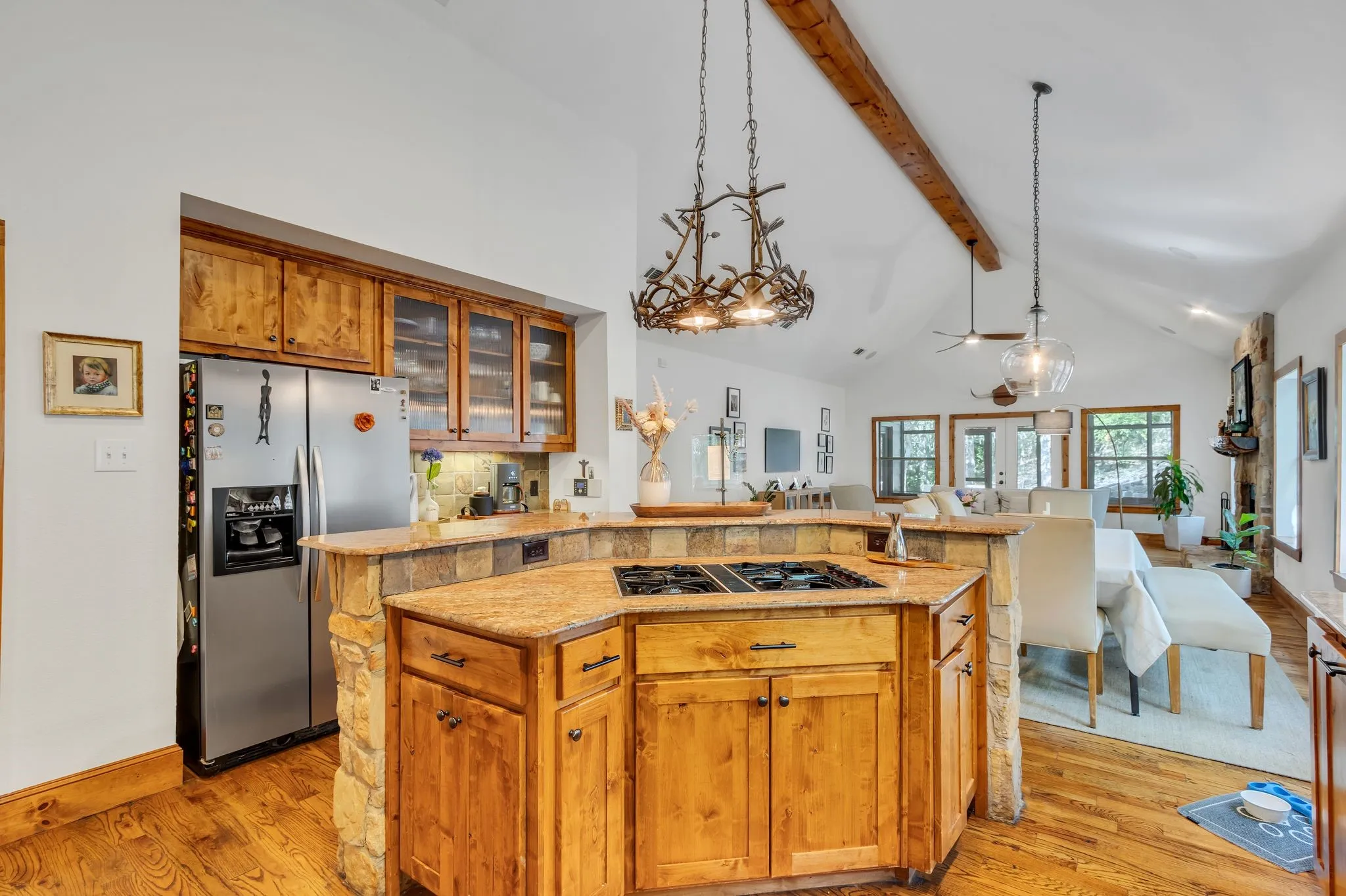 Kitchen featuring a built-in cooktop island with stone accents and a granite-style countertop