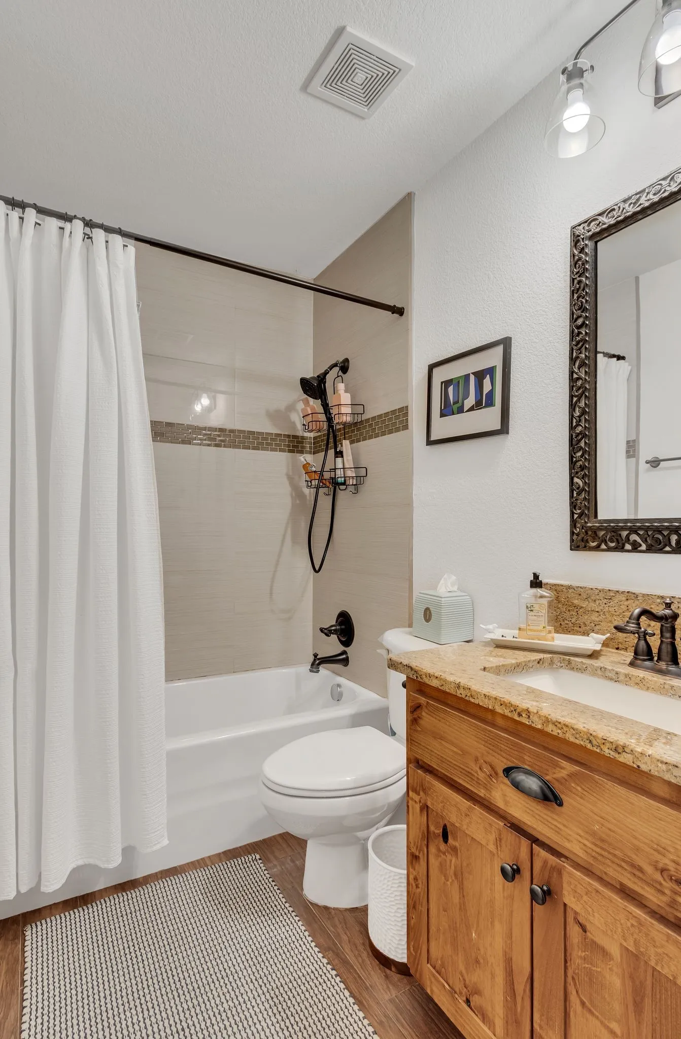 Bathroom featuring a wood-finish vanity with a light-toned countertop, an integrated sink, and dark-finished hardware